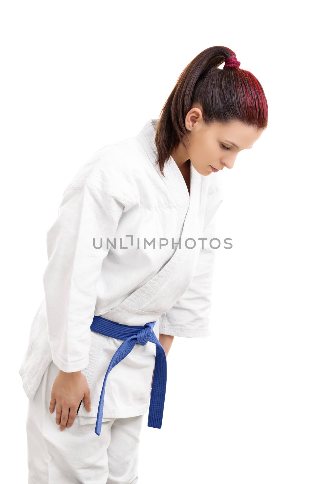 Portrait of a young girl in a white kimono with blue belt bowing, isolated on white background.