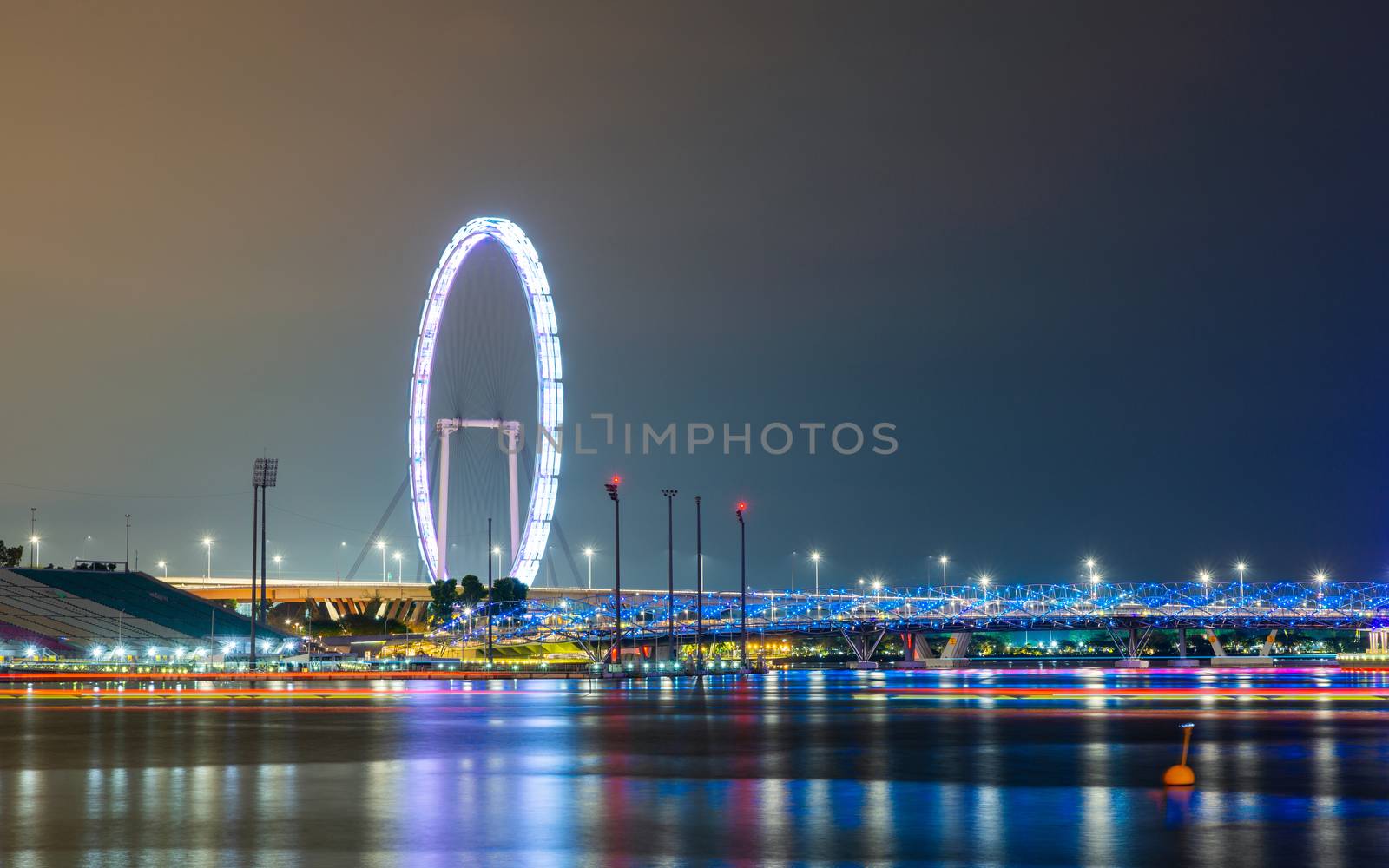 The Singapore Flyer and Helix Bridge at night, colorful lightrails created by boats.