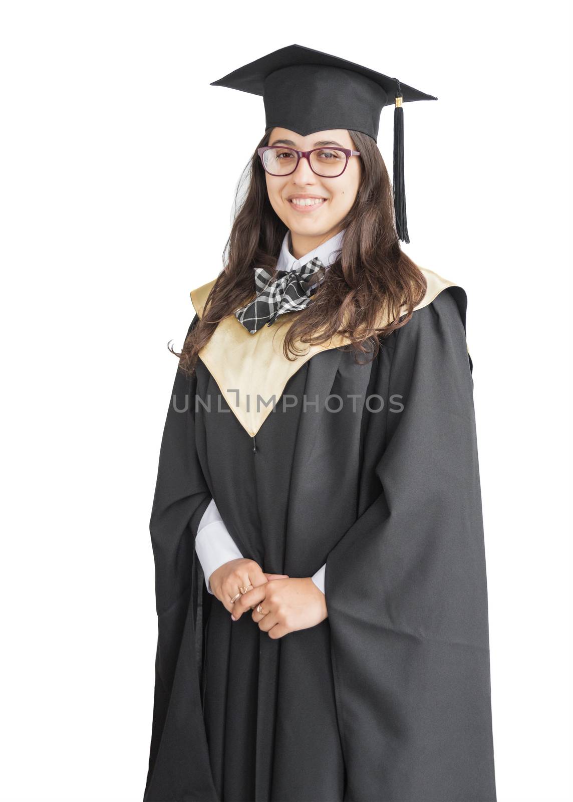 Young girl graduate of the University with eyeglasses, academic cap and black gown, standing isolated on white background