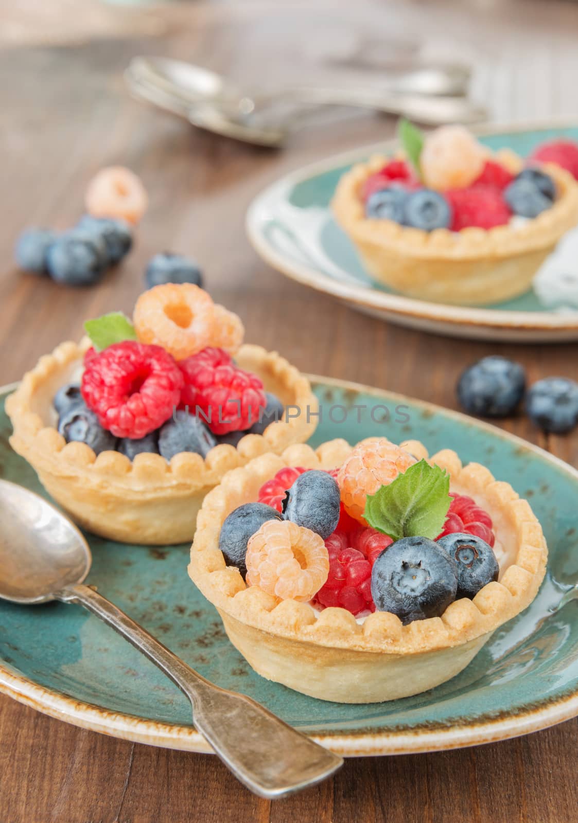 Fruit tartlets with cream, raspberries and blueberries on a blue vintage plates