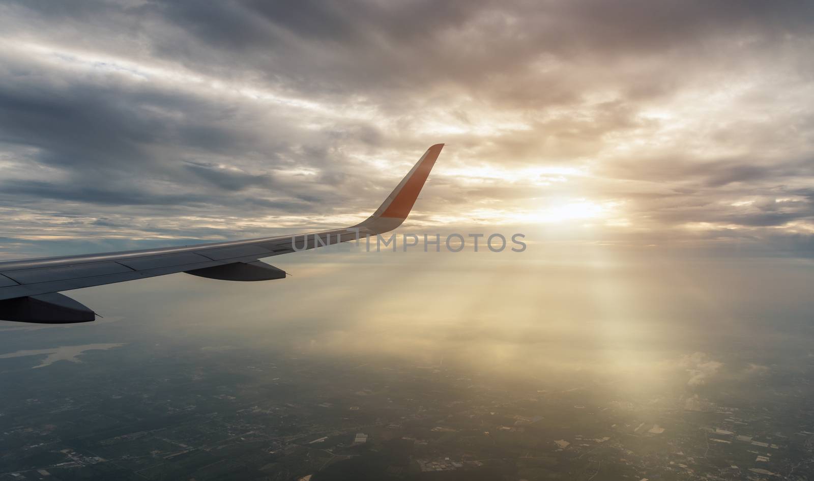 Aircraft wing transportation plane flying over clouds with sunlight