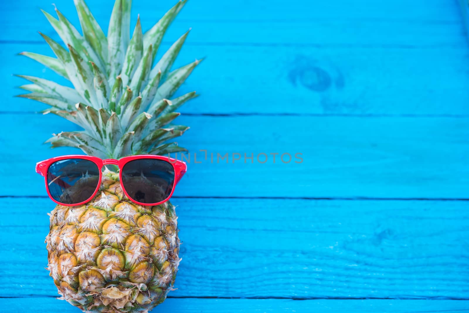 Holiday pineapple have sunglasses on blue   wooden background by Sorapop