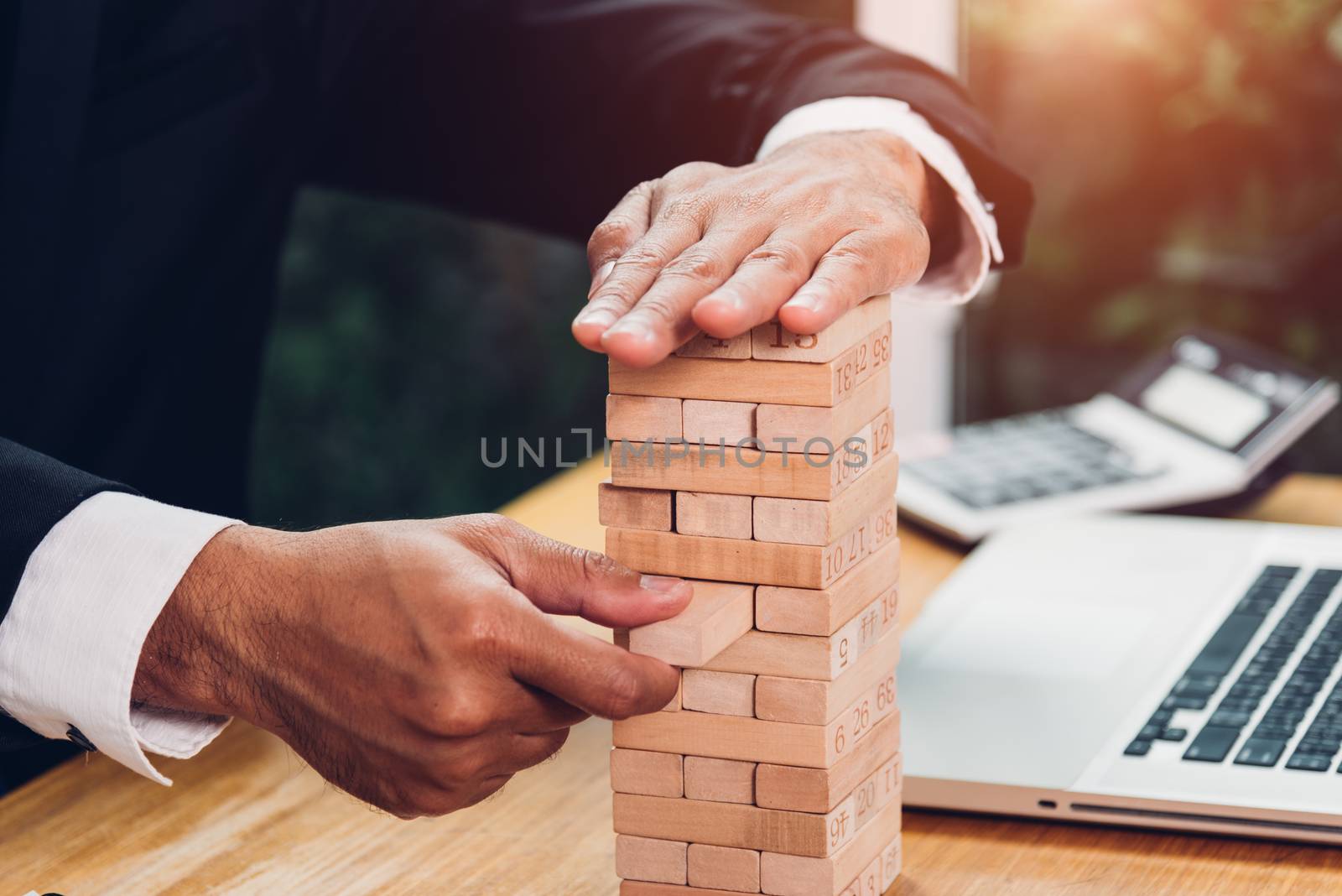 Business man strategy risk game pull tower block wood on desk office, management concept