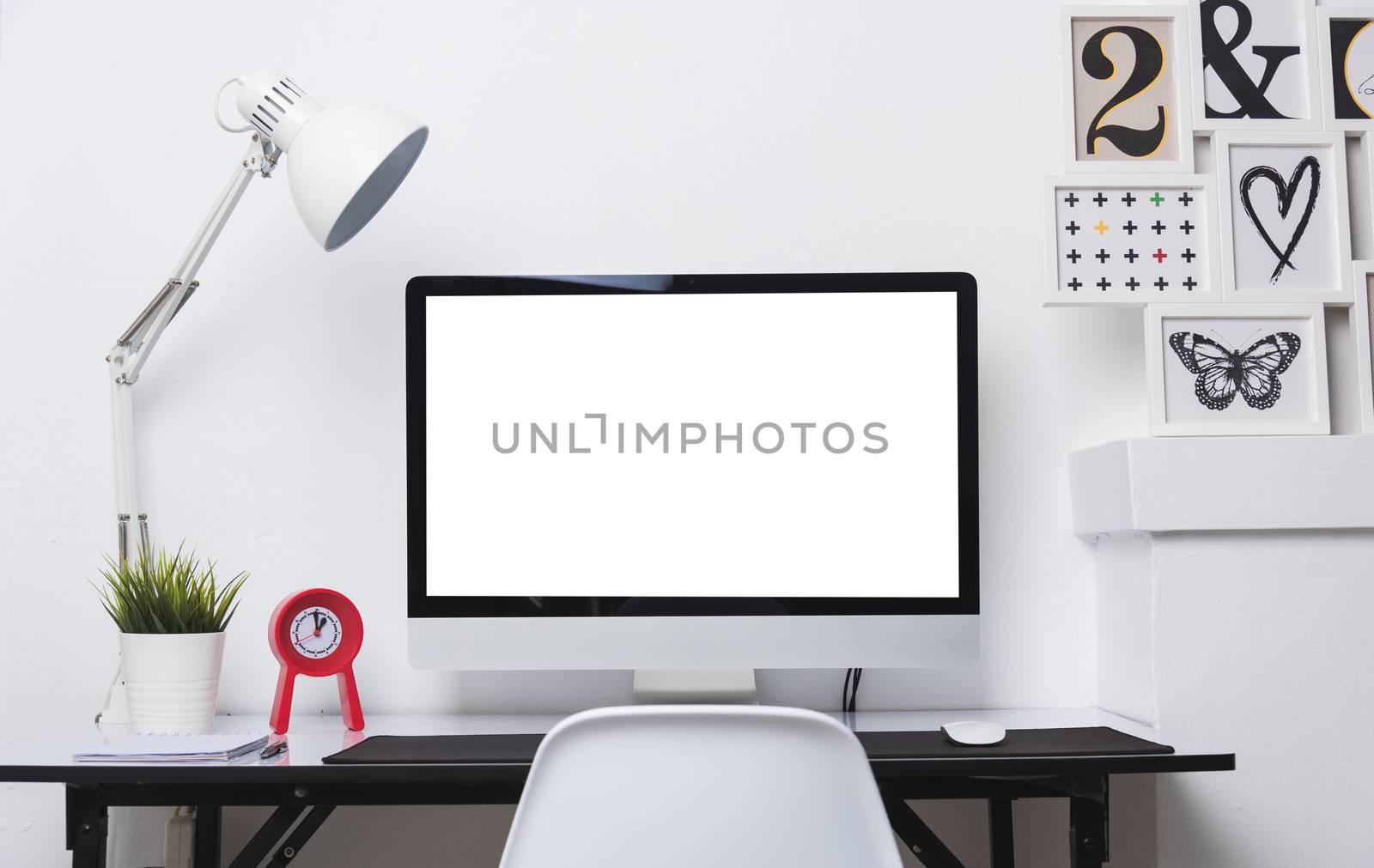 Computer blank white display with work desk in office interior white wall