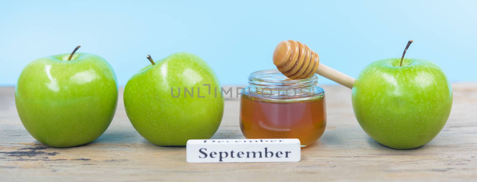 Jewish holiday, Apples Rosh Hashanah on the photo have honey in jar and green apples on wooden with blue background