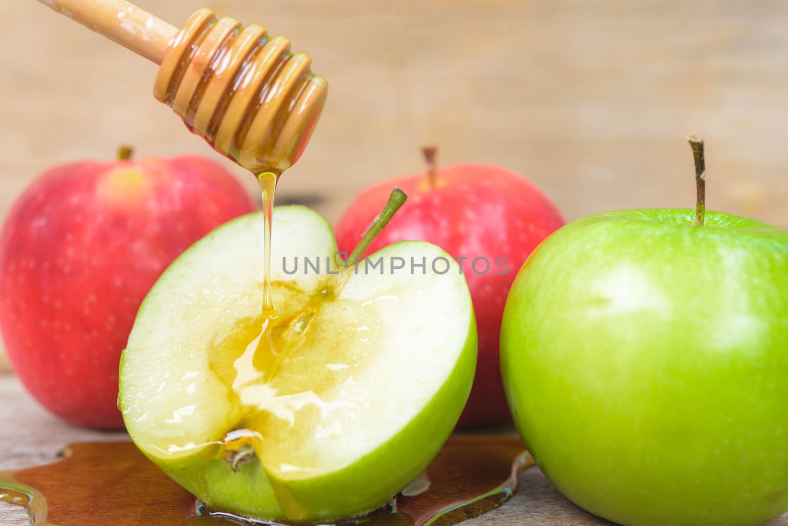 Jewish holiday, Apple Rosh Hashanah, the photo have honey in jar and drop honey on green apples on wooden background