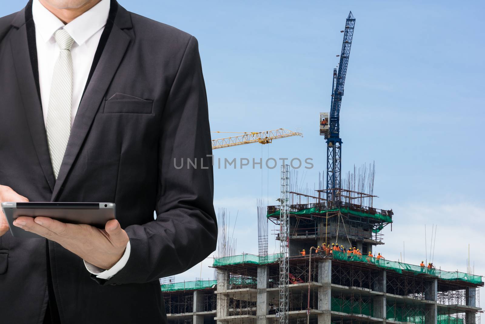 Engineering working hold tablet in front of construction site.