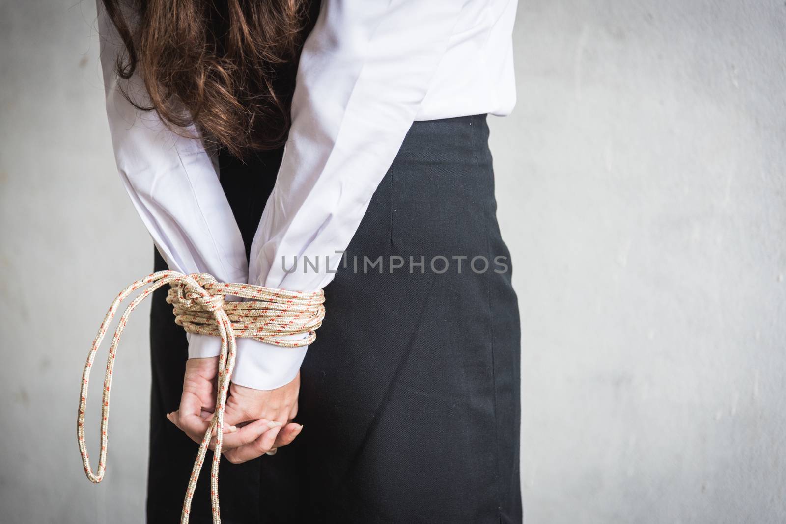 young female hands tied wrist with rope by Sorapop