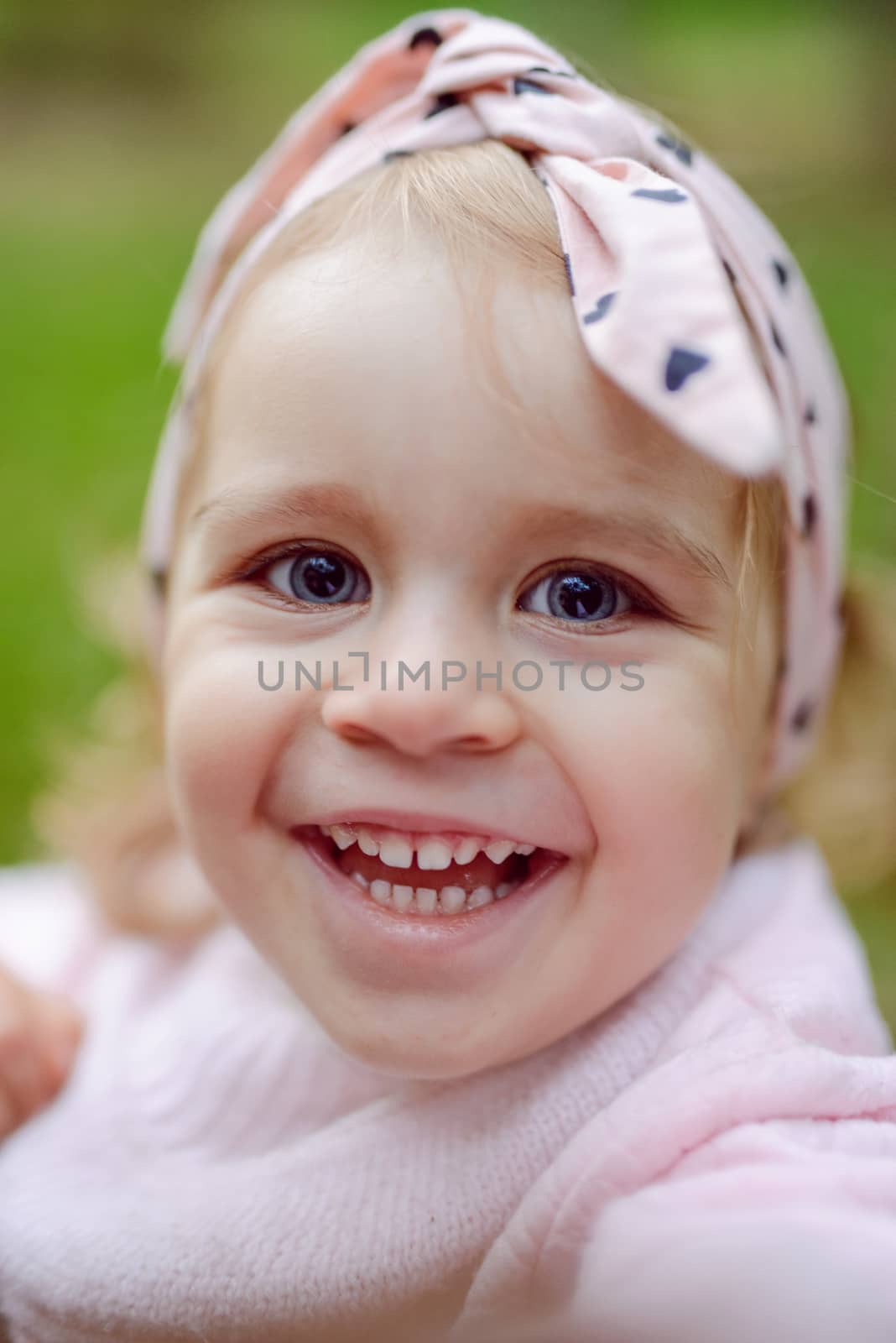 beautiful little girl smiling on a sunny day. Blue eyes. head shot.