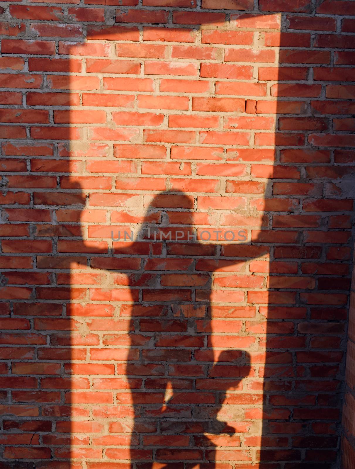 Interior of a Unfinished Red Brick House Walls under Construction without Roofing. People shadow on the wall. Mother, wife and daughter.