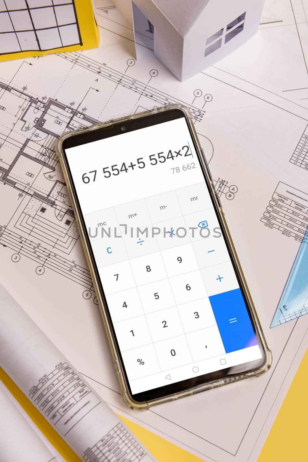 Counting the cost of building a house on a calculator .White family paper house, block of flats. Minimalistic and simple concept, style. Copy space. Vertical orientation