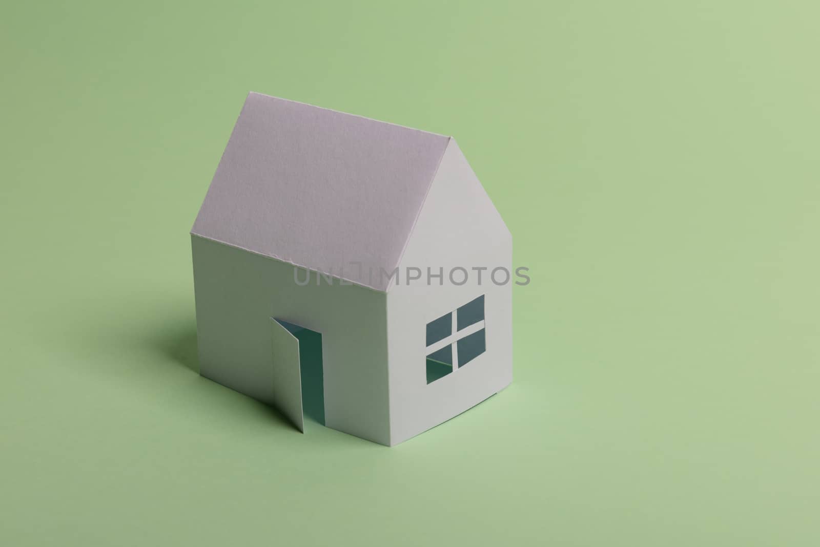 White family paper house in man hand on mint background paper. Minimalistic and simple concept, style. Copy space. Horizontal orientation