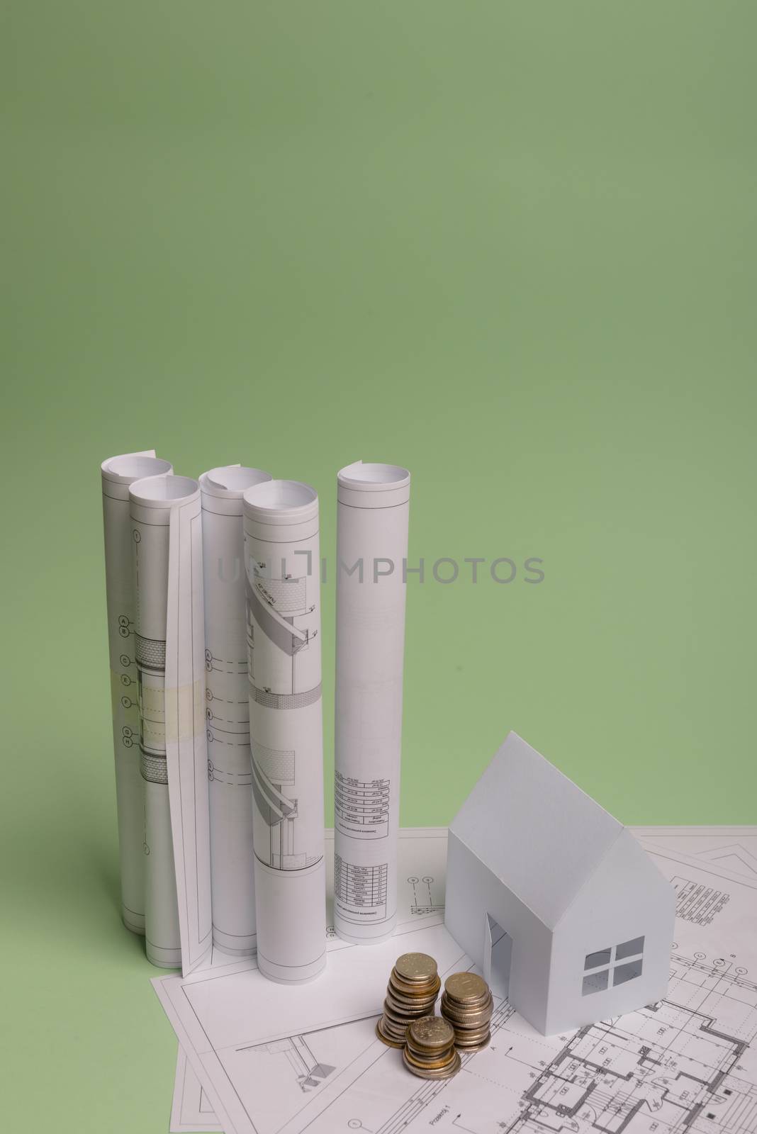 White family paper house , stack of money coins, house projects plan and blueprints on mint background paper. Minimalistic and simple concept, style. Vertical orientation