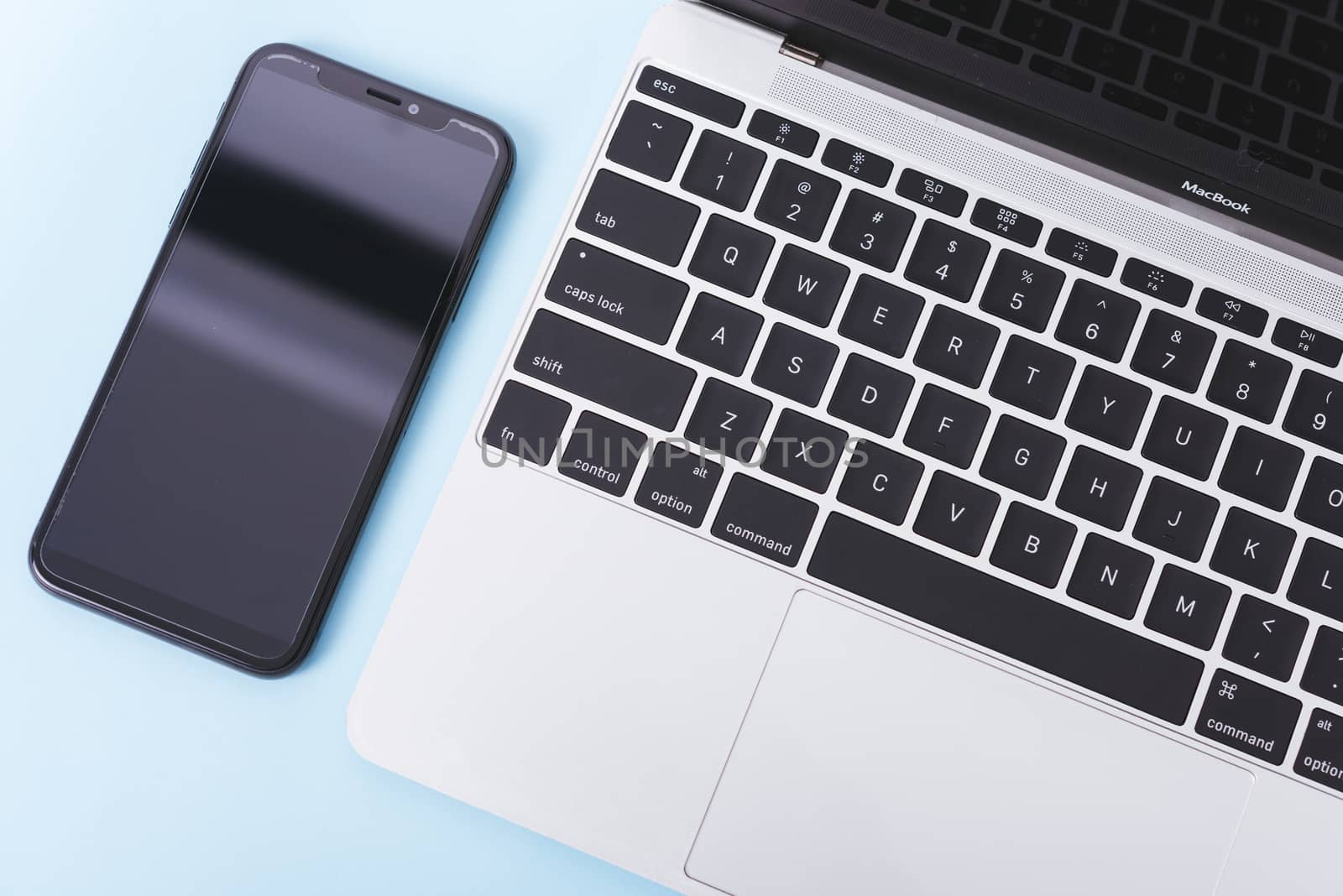 Top view of modern technology smart phone mobile and computer laptop on blue background with copy space