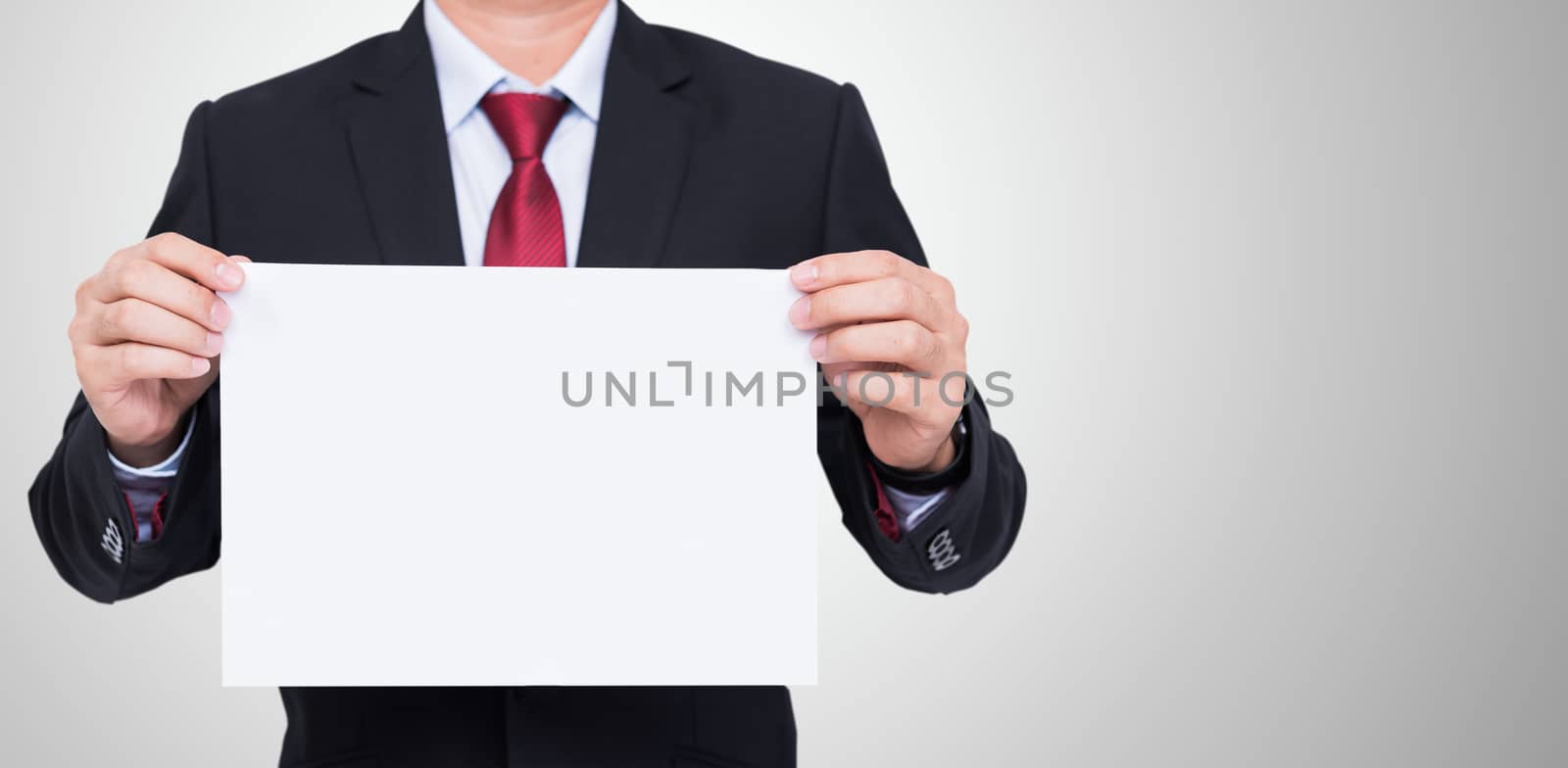 Businessman holding blank white paper for your text message on gray background