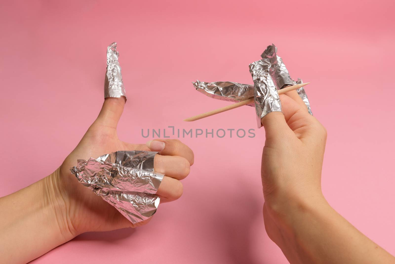 The procedure for removing varnish from nails hybrid nails in progress. Gel nail polish remover foils on woman's hands