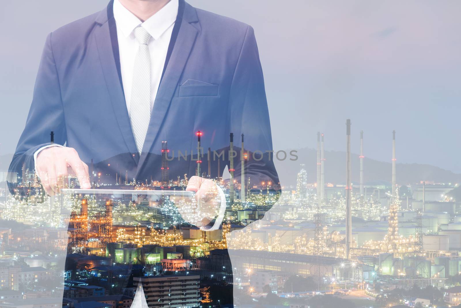 Double exposure of businessman hand hold tablet, oil refinery industry plant, Petroleum energy concept