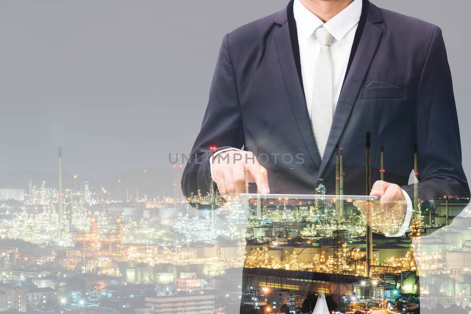 Double exposure of businessman hand hold tablet, oil refinery industry plant, Petroleum energy concept