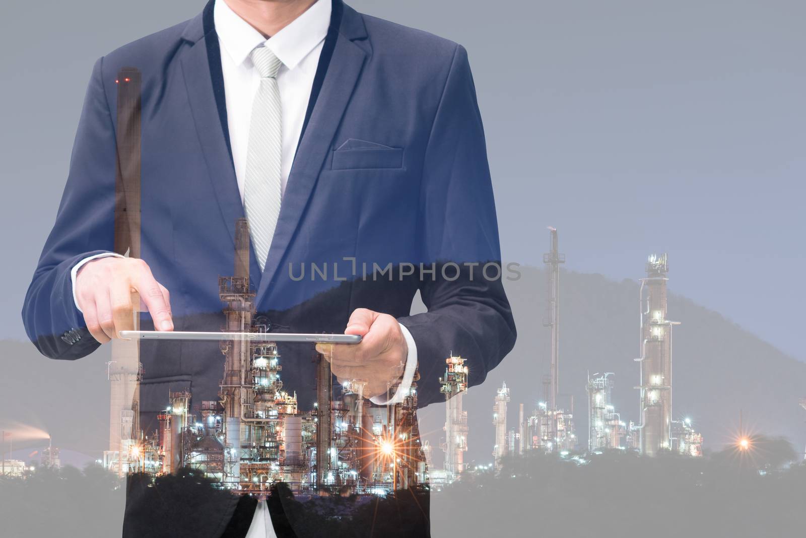 Double exposure of businessman hand hold tablet, oil refinery industry plant, Petroleum energy concept