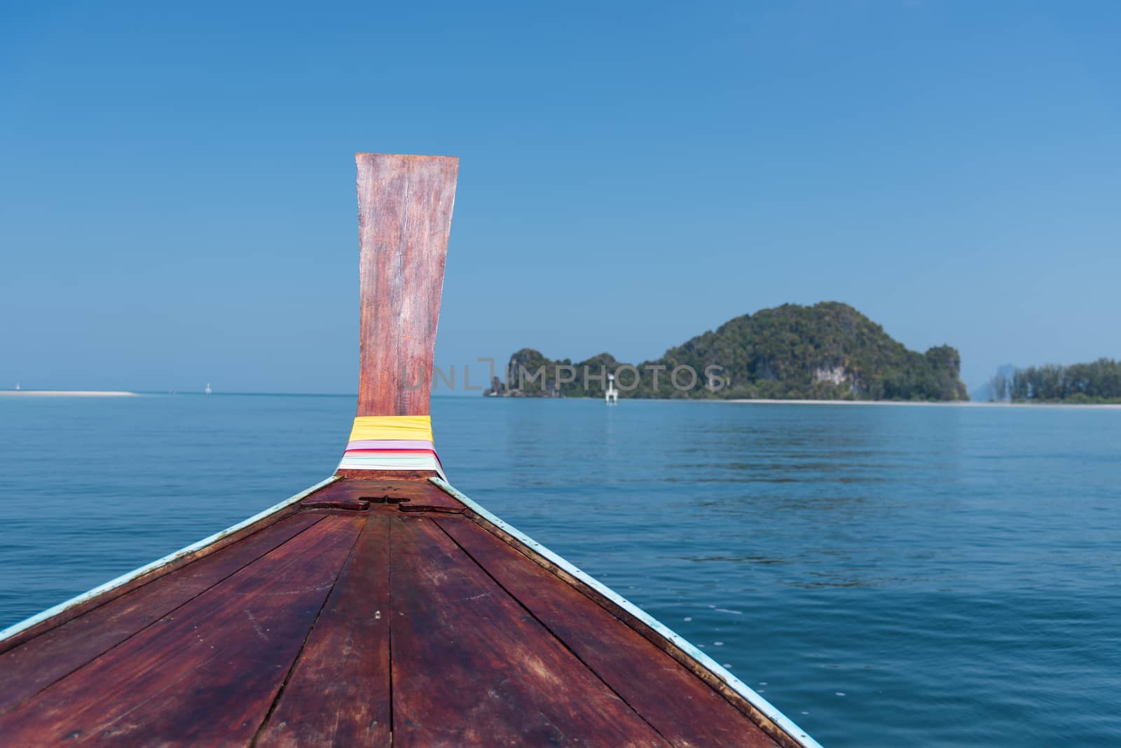 Thai wooden head longtail boat heads toward the tropical Andaman shores at Thailand andaman
