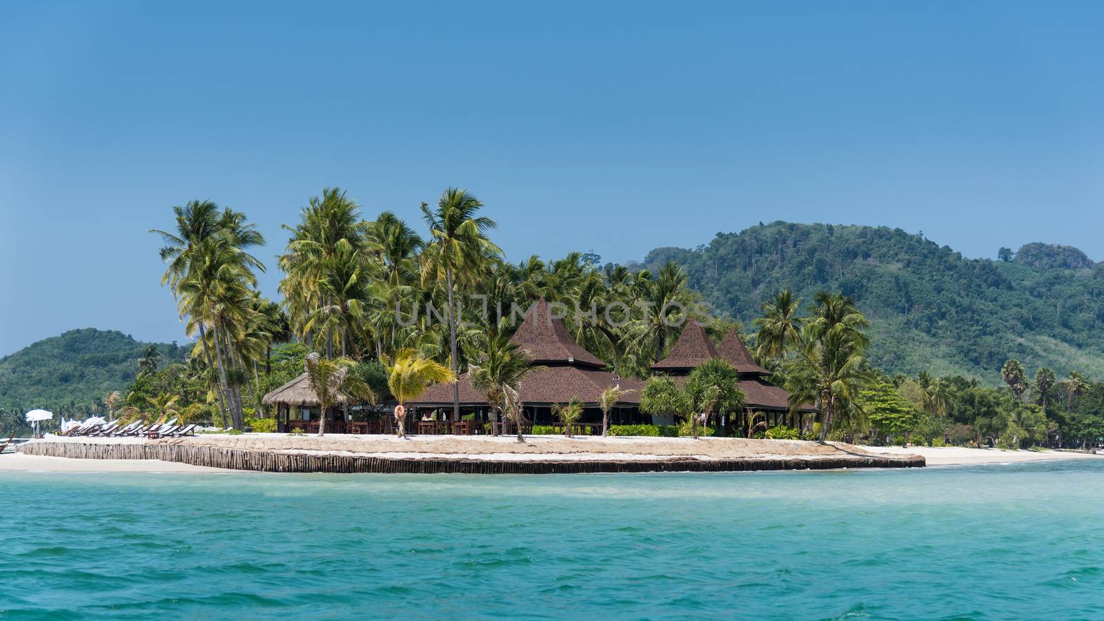 Over water bungalows on island beach with palm trees