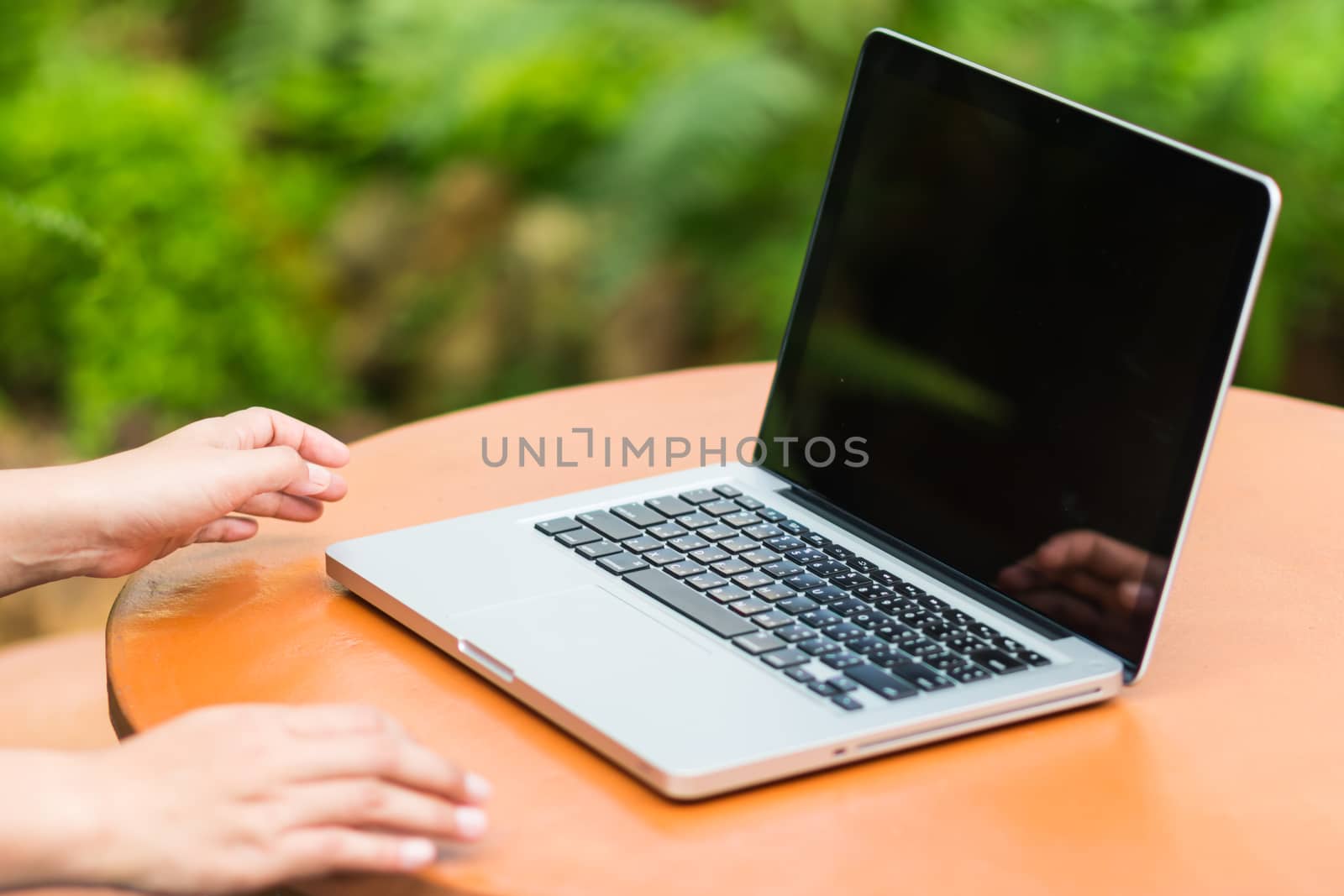 Woman hands typing on laptop outdoors in cafe