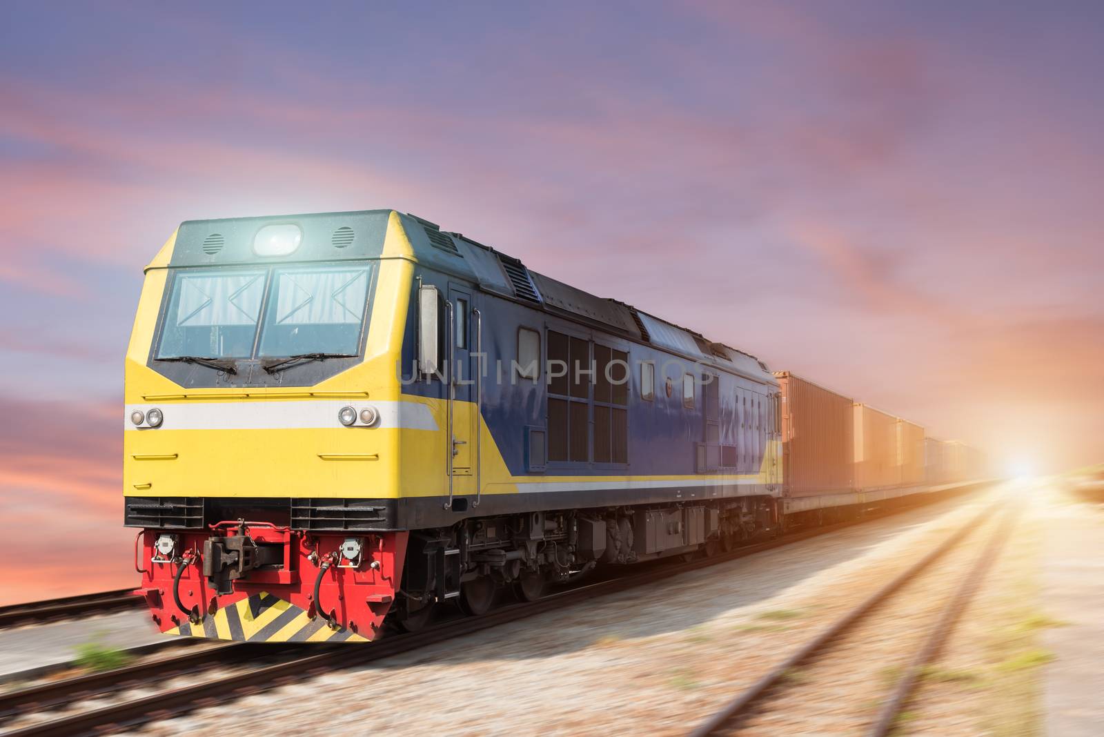 Fast freight blue train at sunset with motion blur