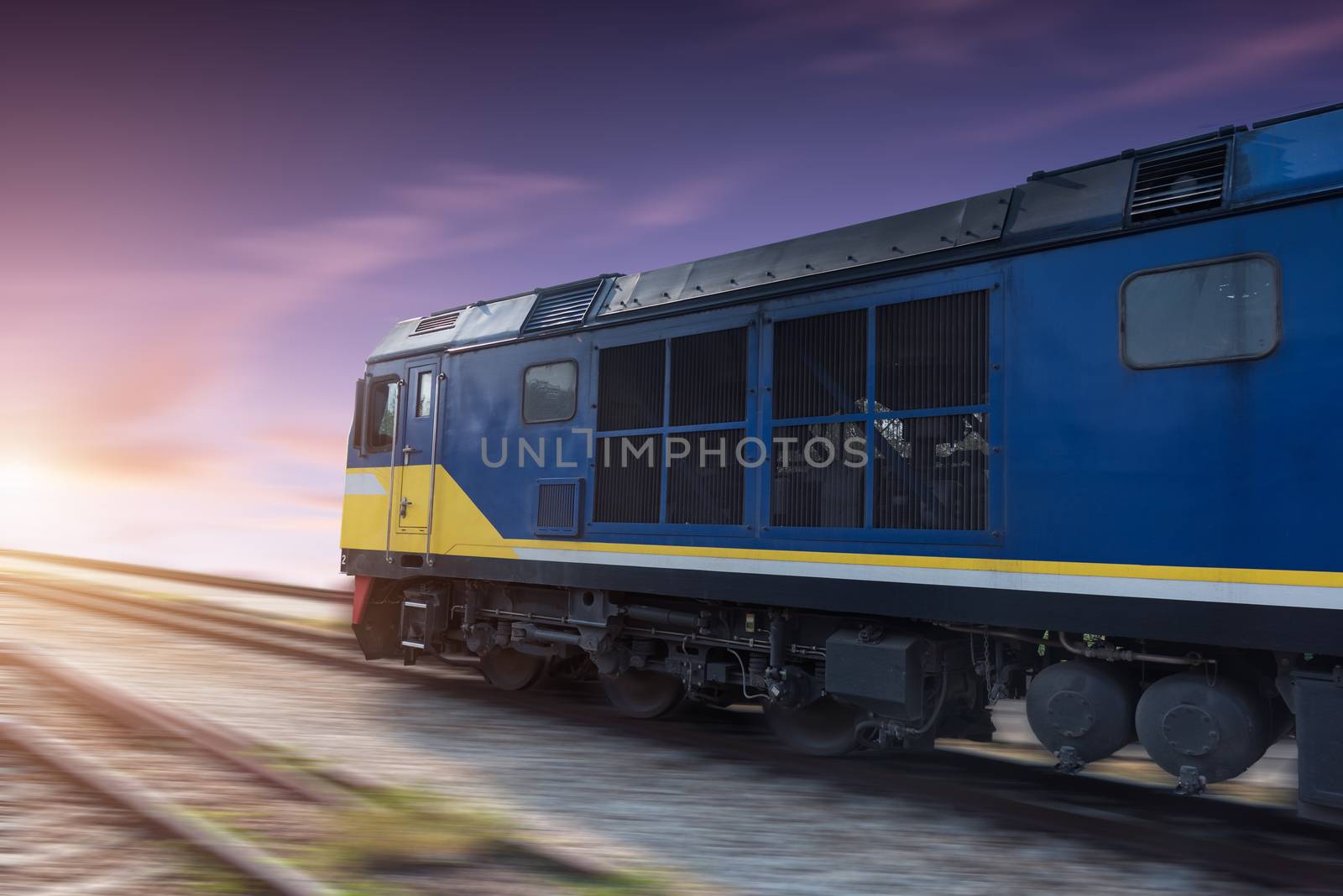 Fast freight blue train at sunset with motion blur