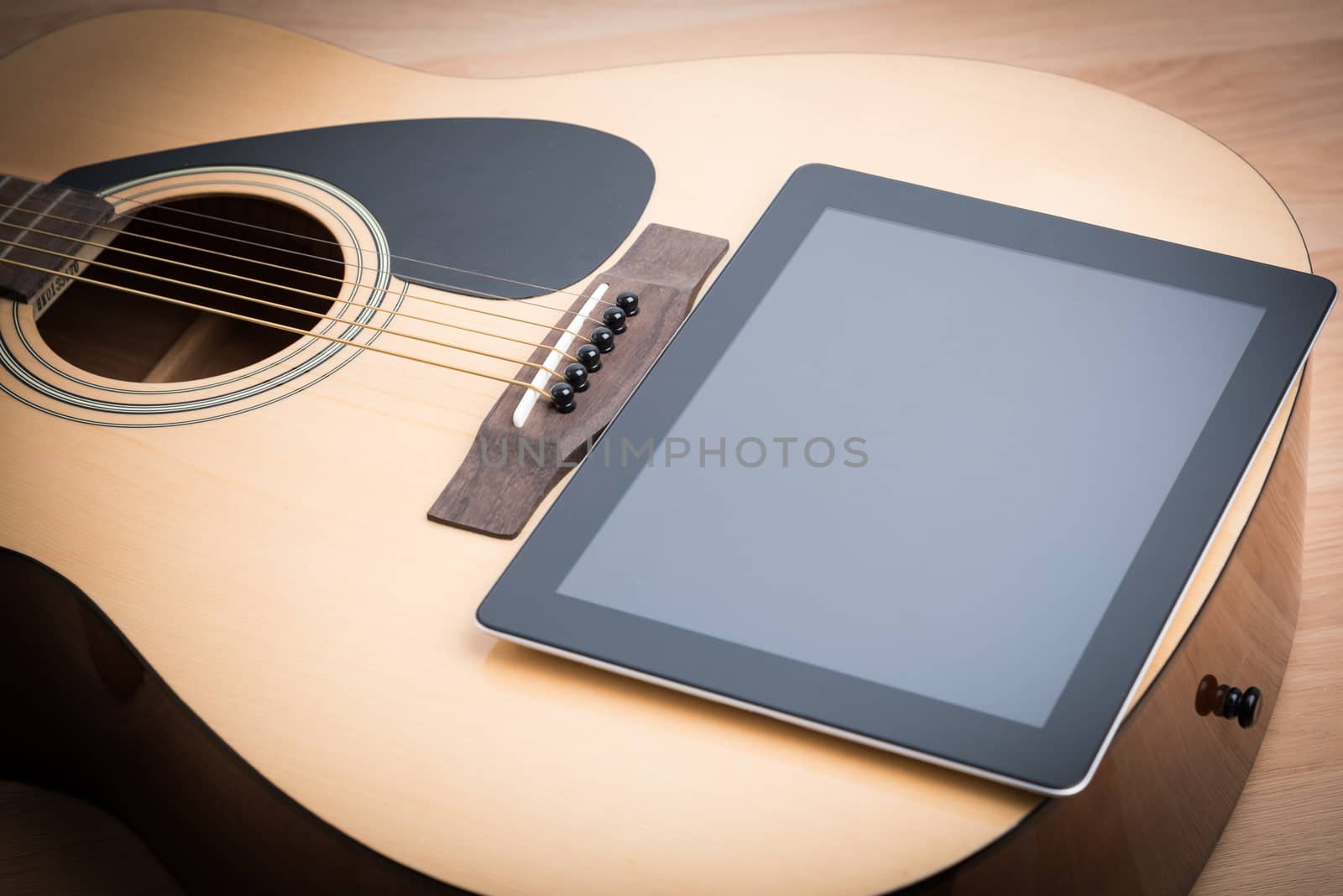Acoustic guitar with digital tablet on the wooden table