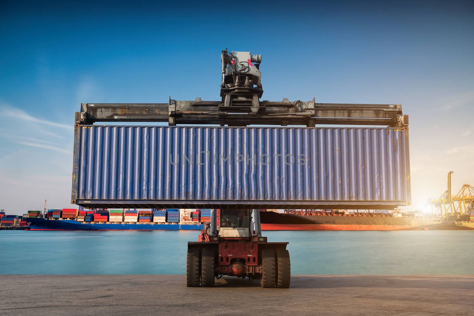 Forklift handling container box loading at port cargo at sunset