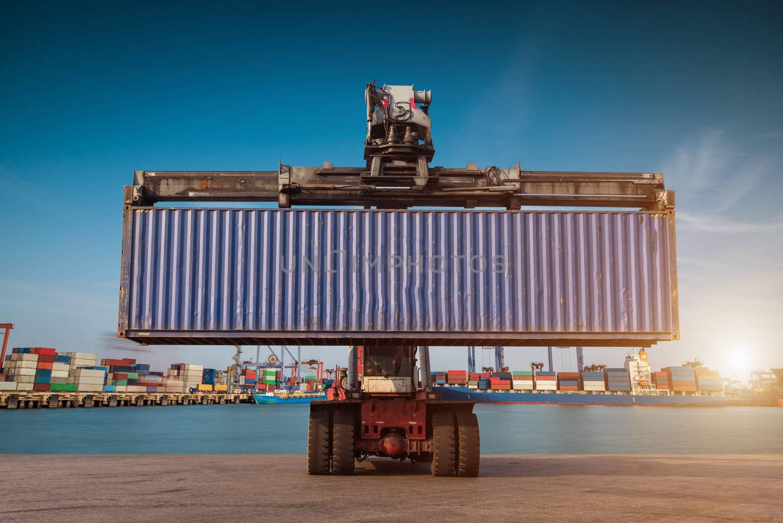 Forklift handling container box loading at port cargo at sunset