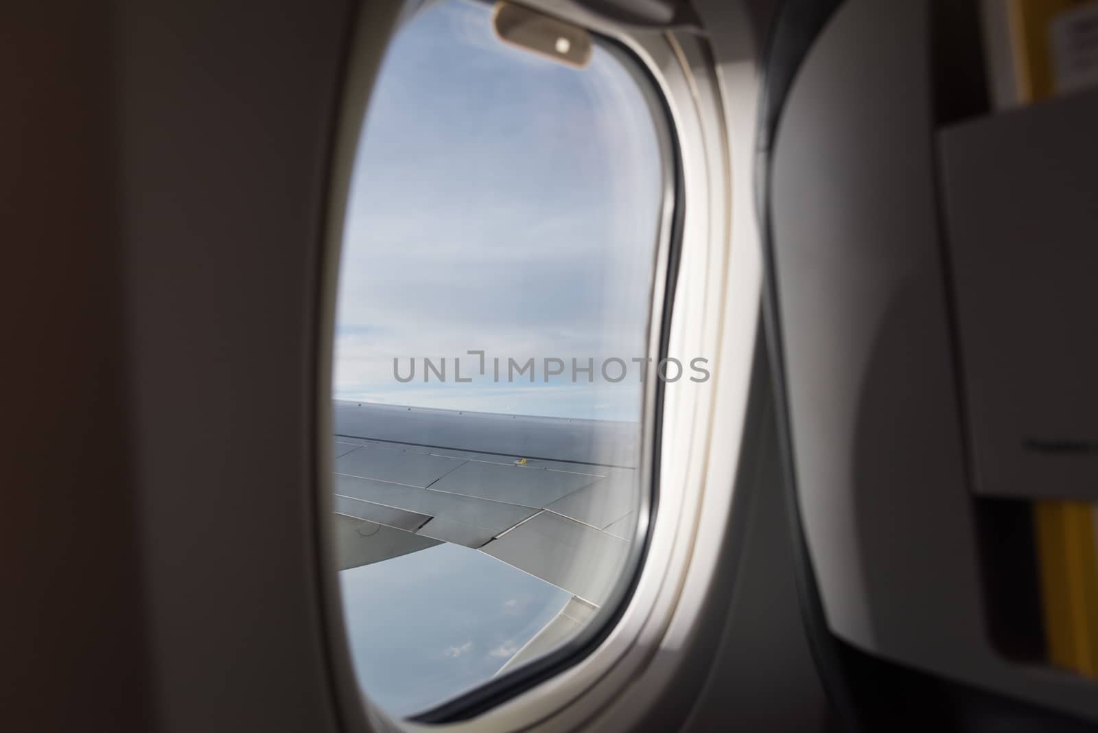 Clouds sky and aircraft wing as seen through window of aircraft