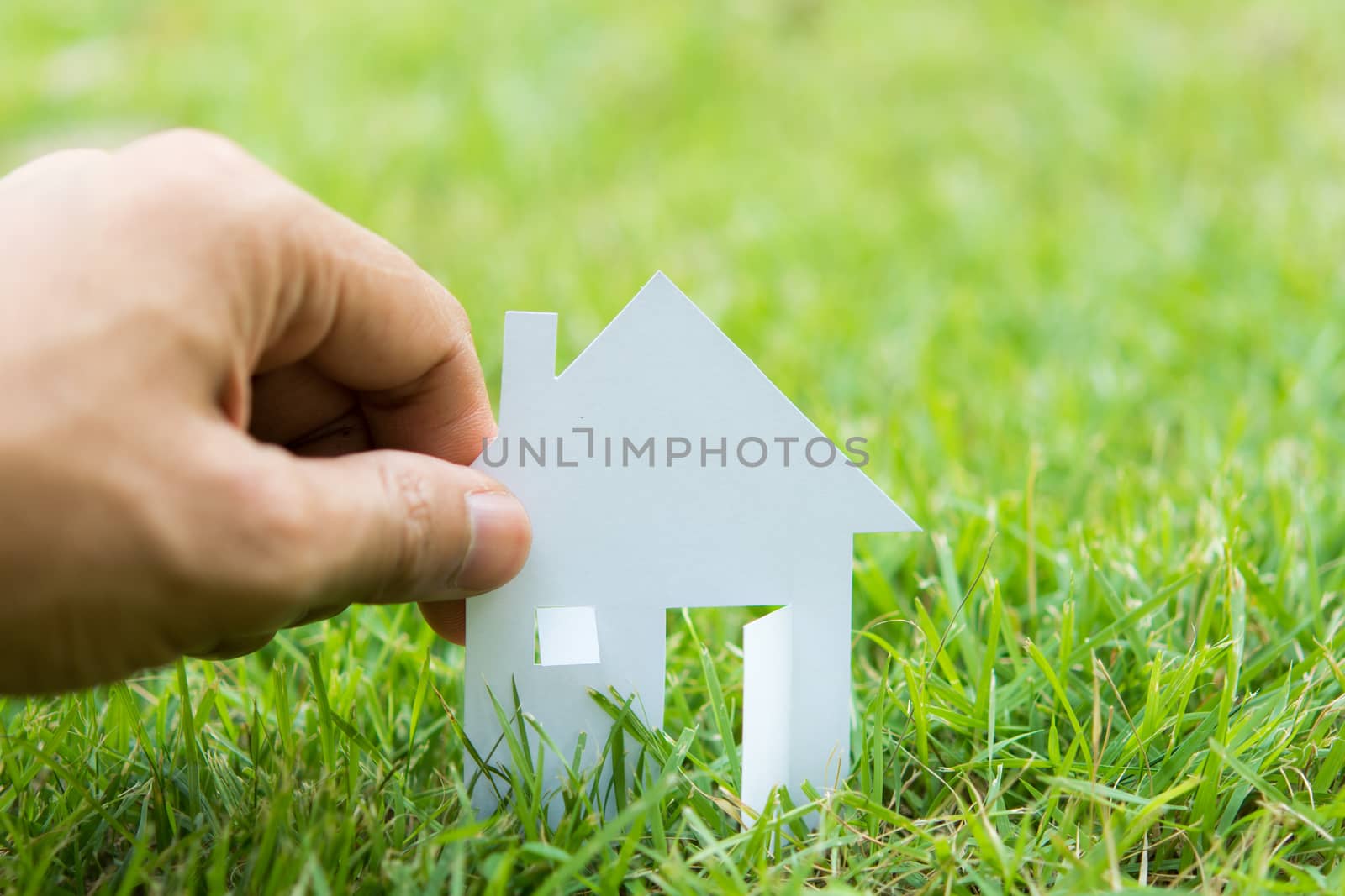 concept image of make house with white paper cut on green grass background