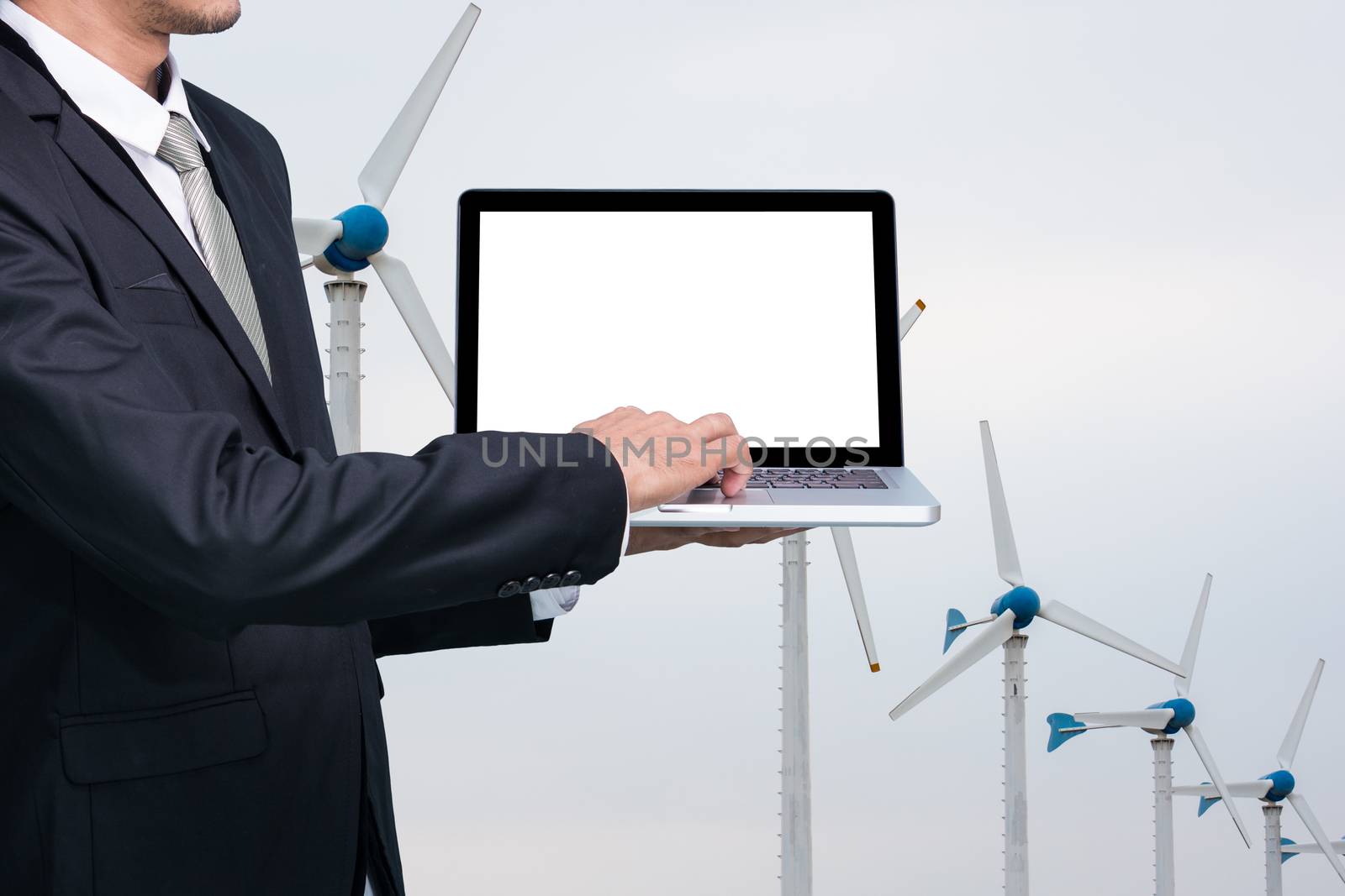 Engineering working hold conputer notebook in front of Wind Turbine Power Generator Station