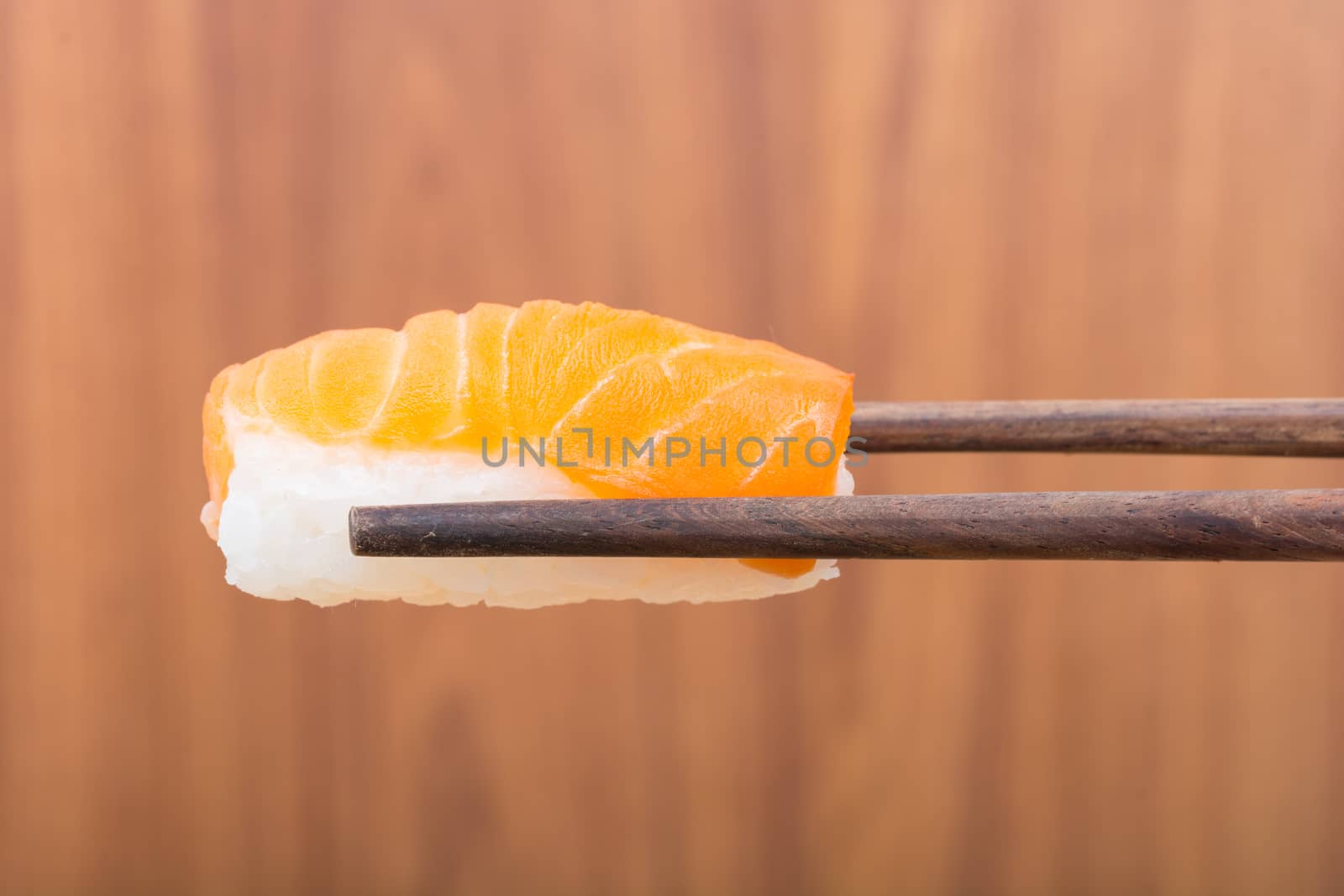 Sushi roll with black chopsticks on wooden background