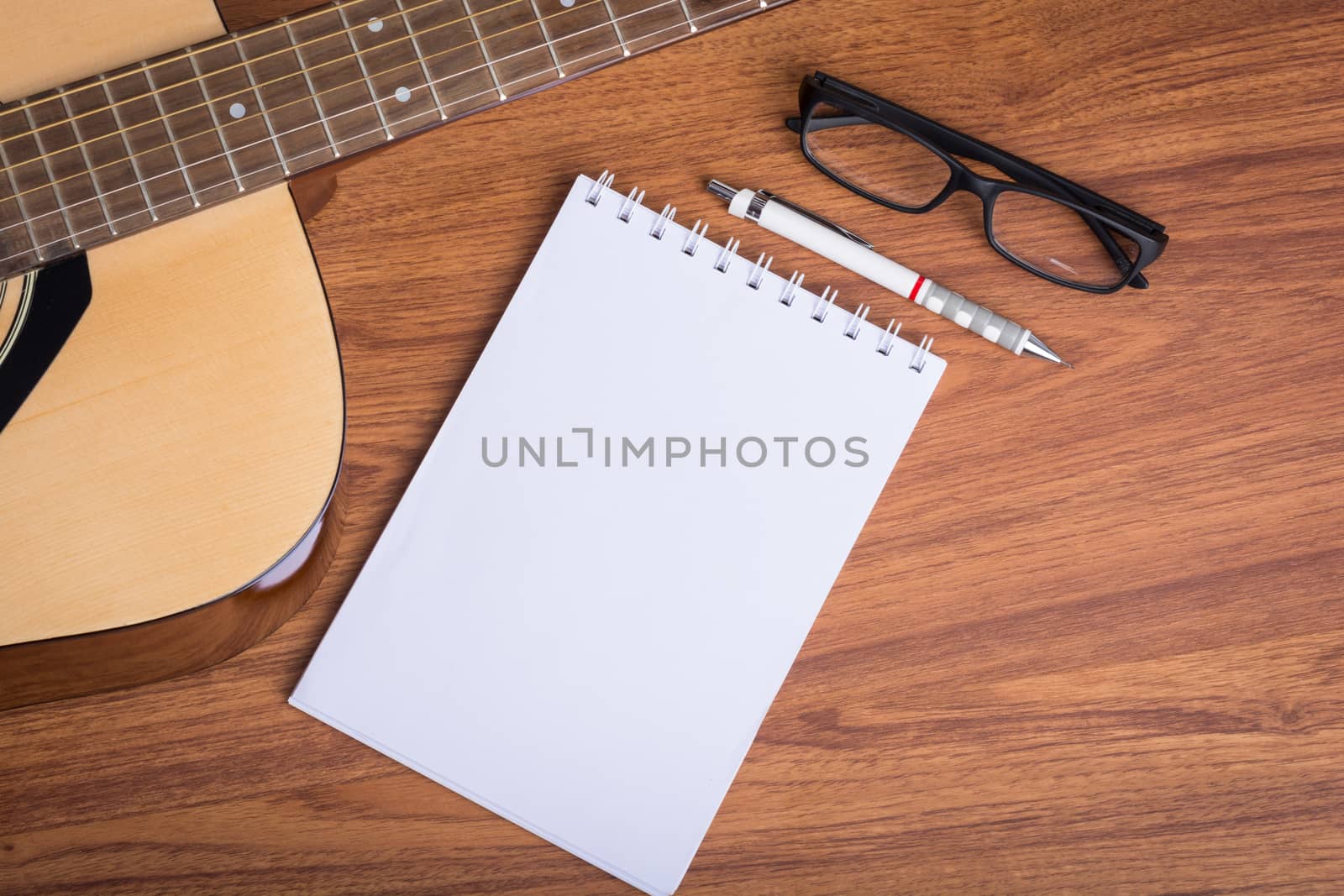 guitar notebook, pencil and eyeglasses on wooden background