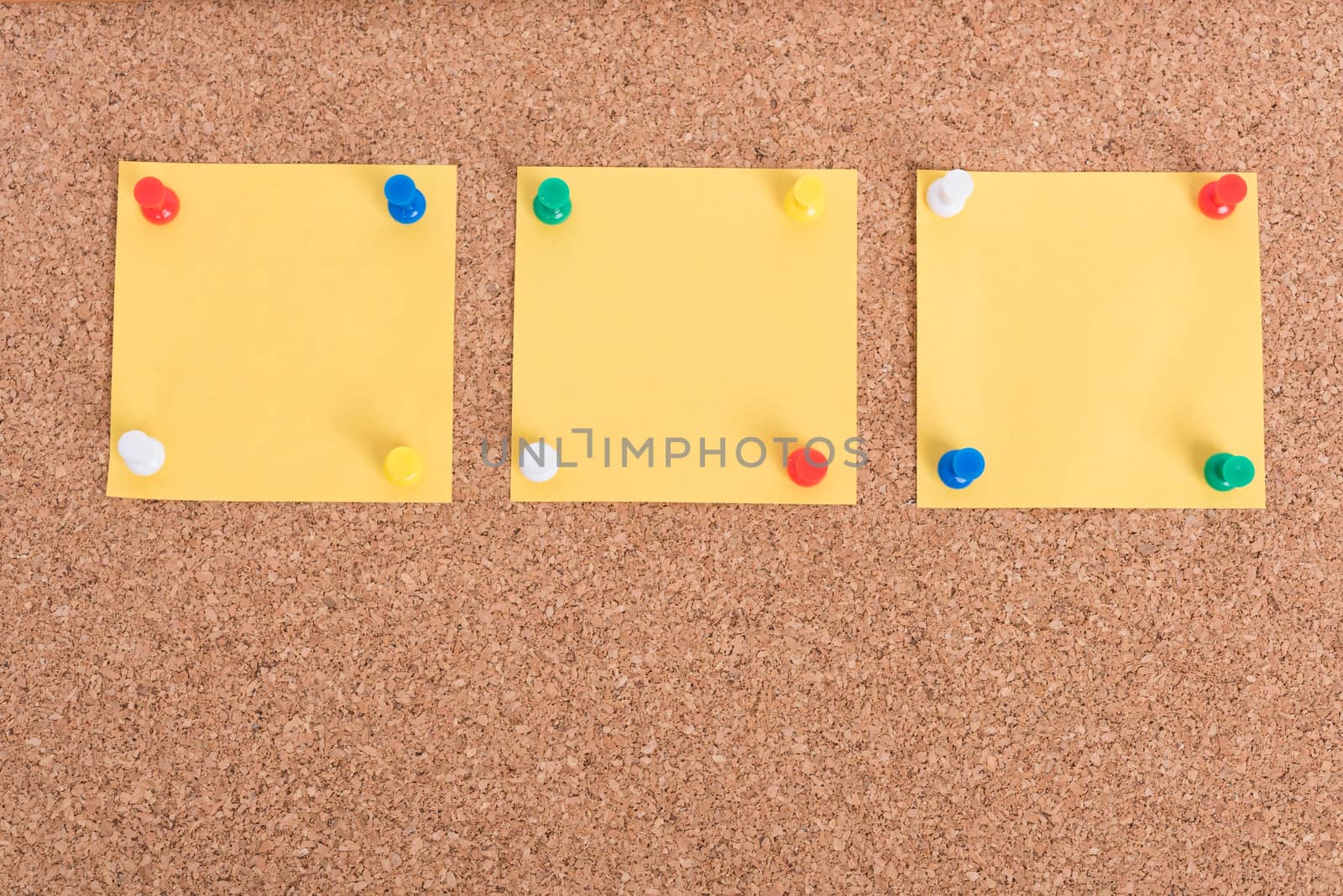 Yellow blank note papers with pin on wooden board background