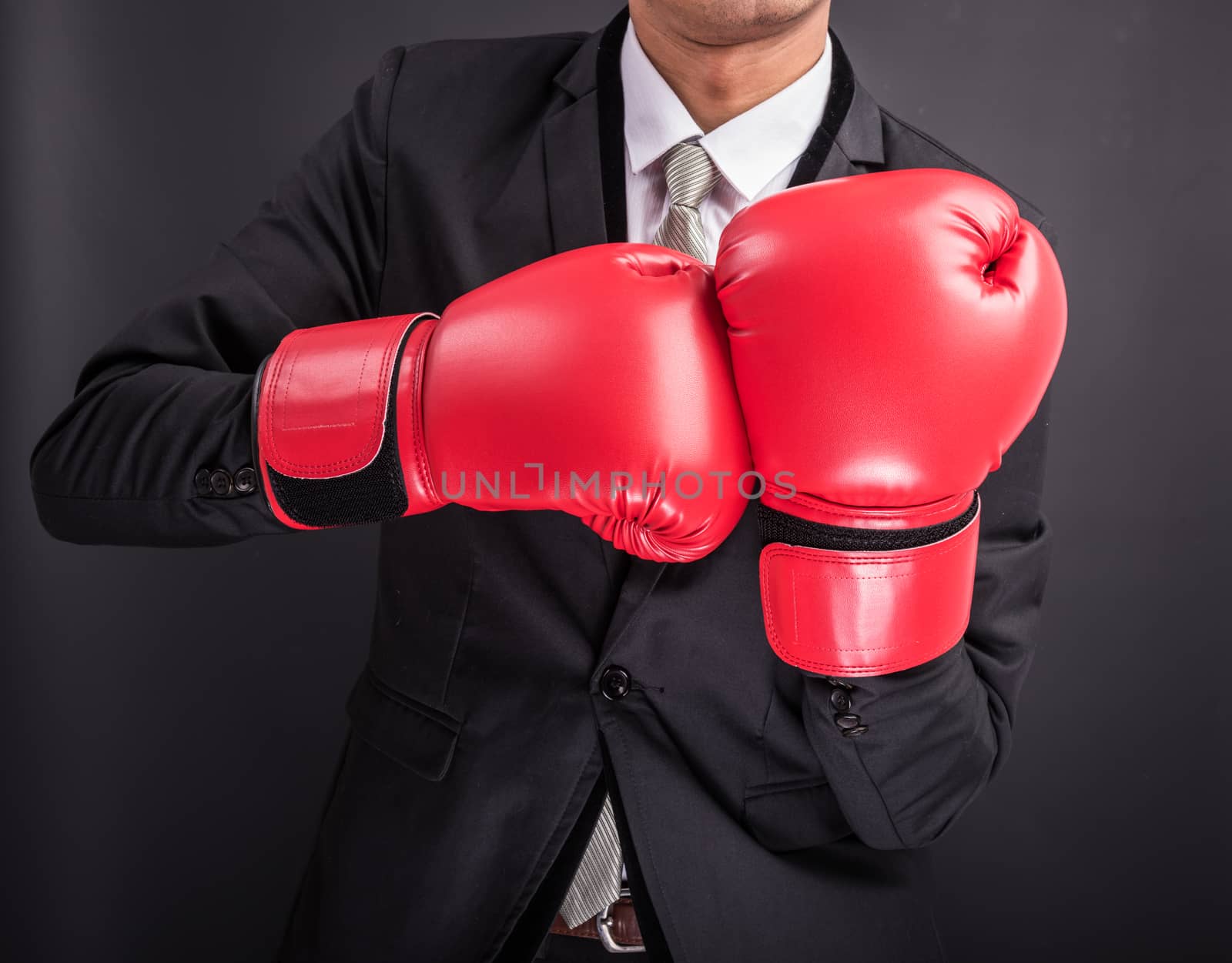 Young businessman with boxing gloves isolated on black background