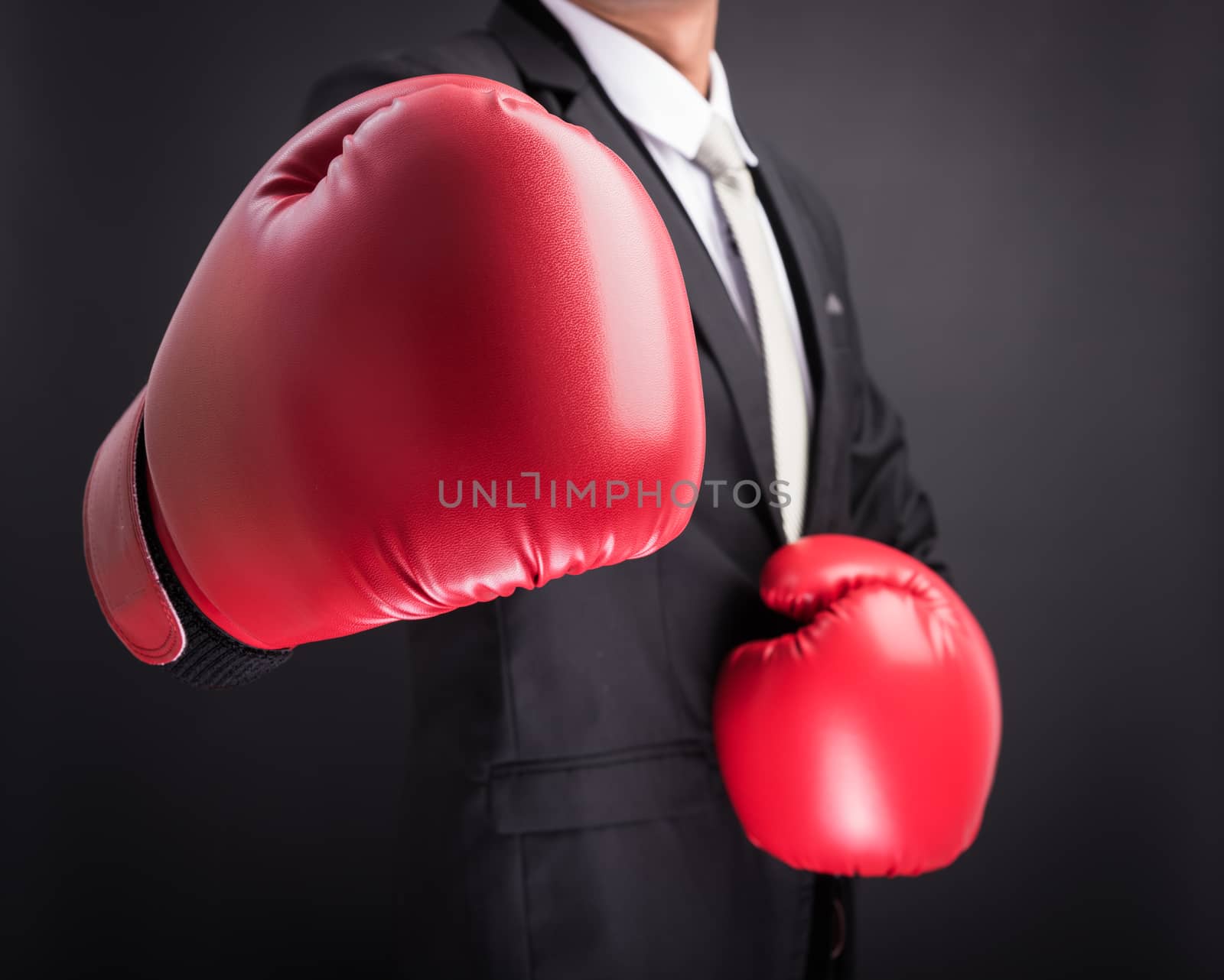 Young businessman with boxing gloves isolated on black background