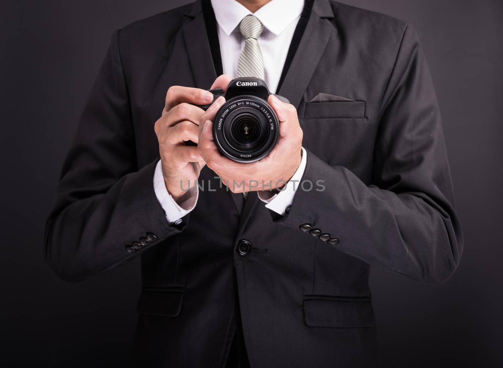 Young photographer man holding camera isolated on black background