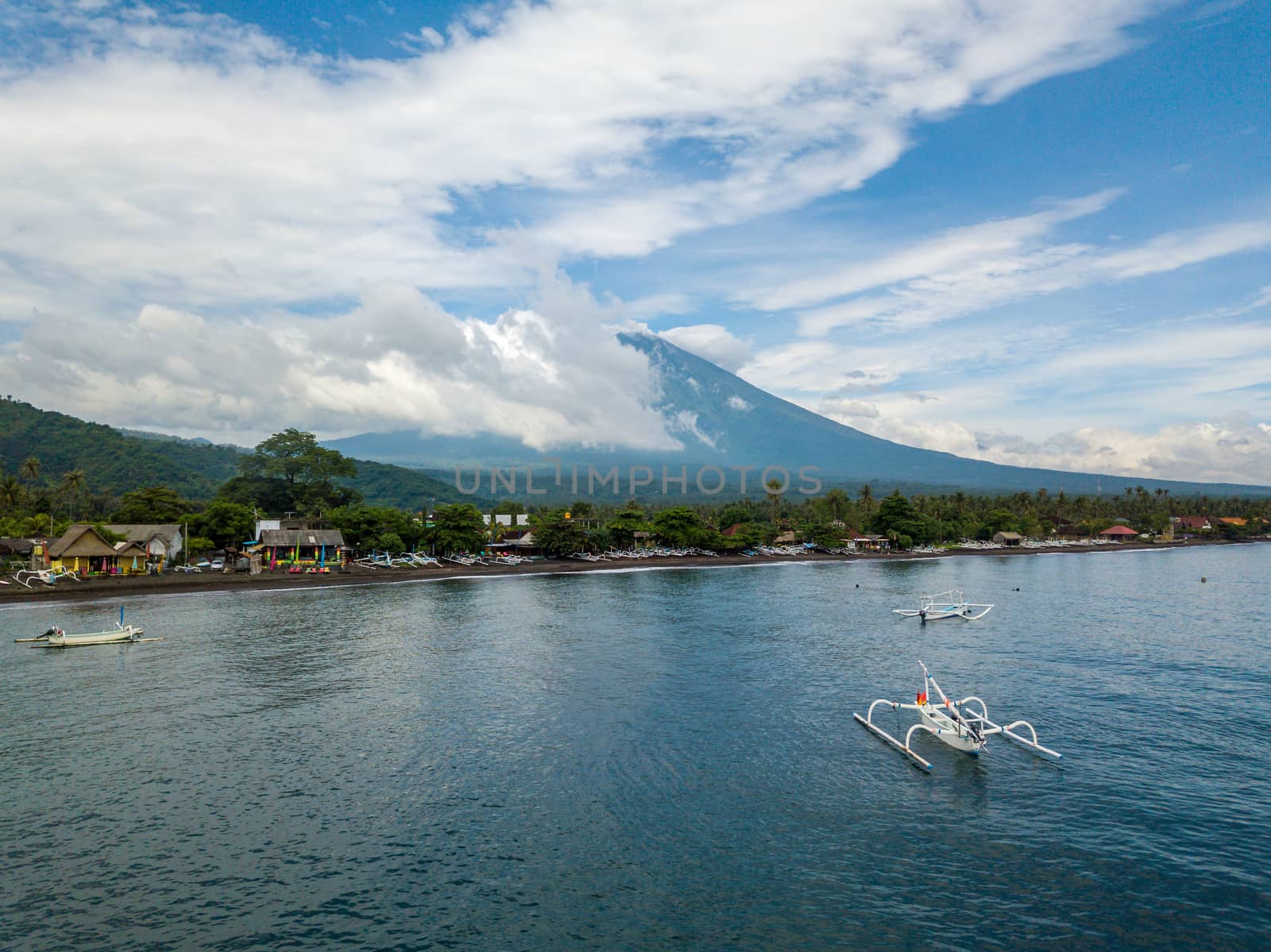 Aerial view of Amed Beach and Mount Agung volcano in Bali, Indonesia. Traditional fishing boats called jukungs in the foreground.