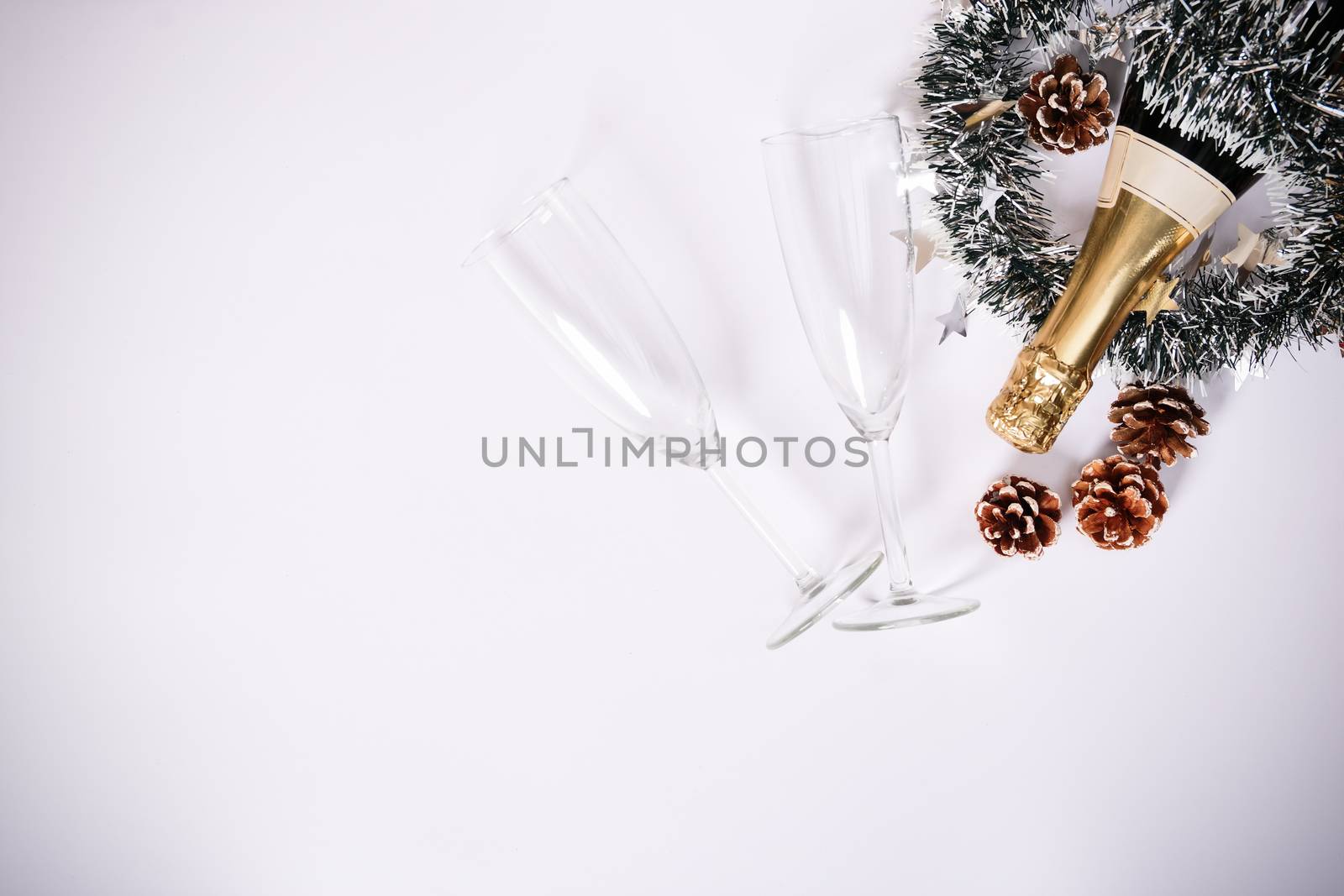 Champagne bottle with two glasses, garland and pinecone decorati by Mendelex