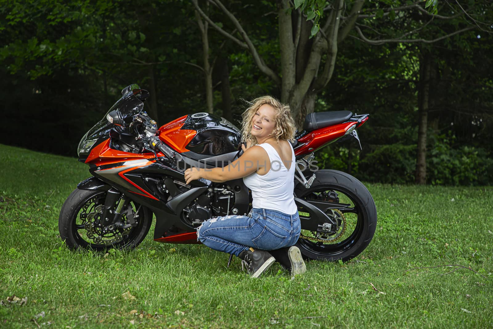 Young woman working on a sport motocyle with a big smill