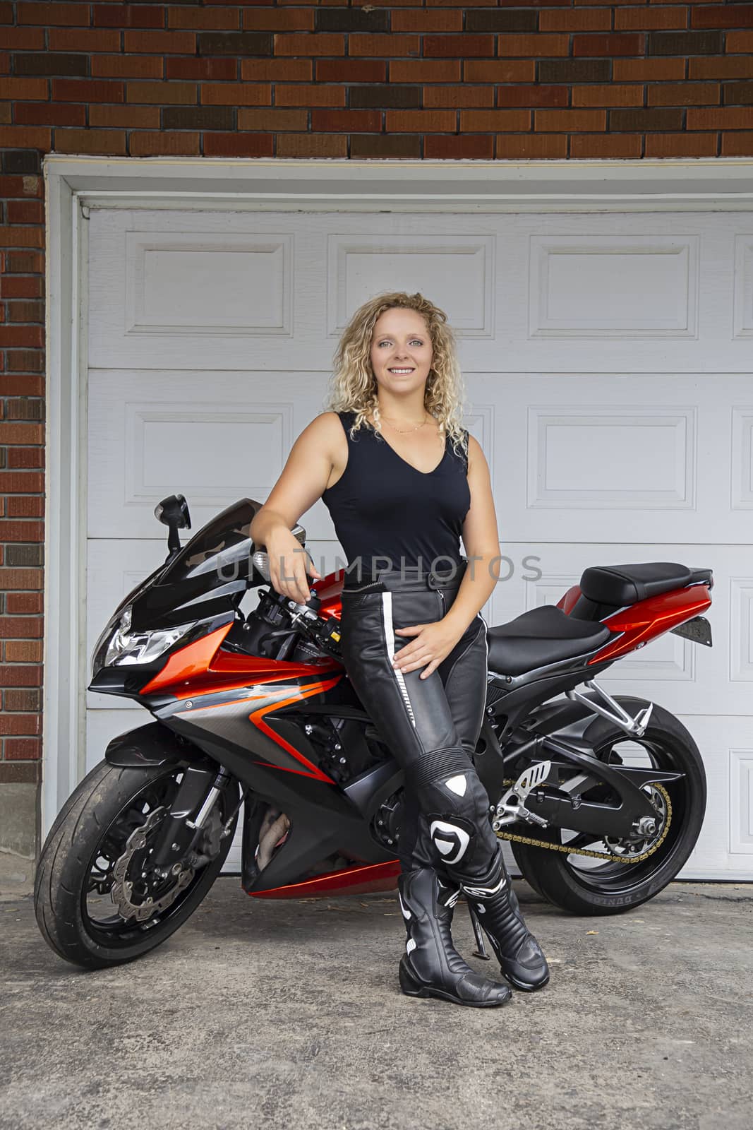 Twenty something blond woman, standing in front of her motocyle