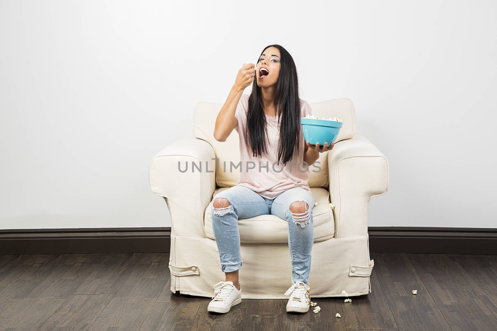 young millennial girl eating a handful of popcorn