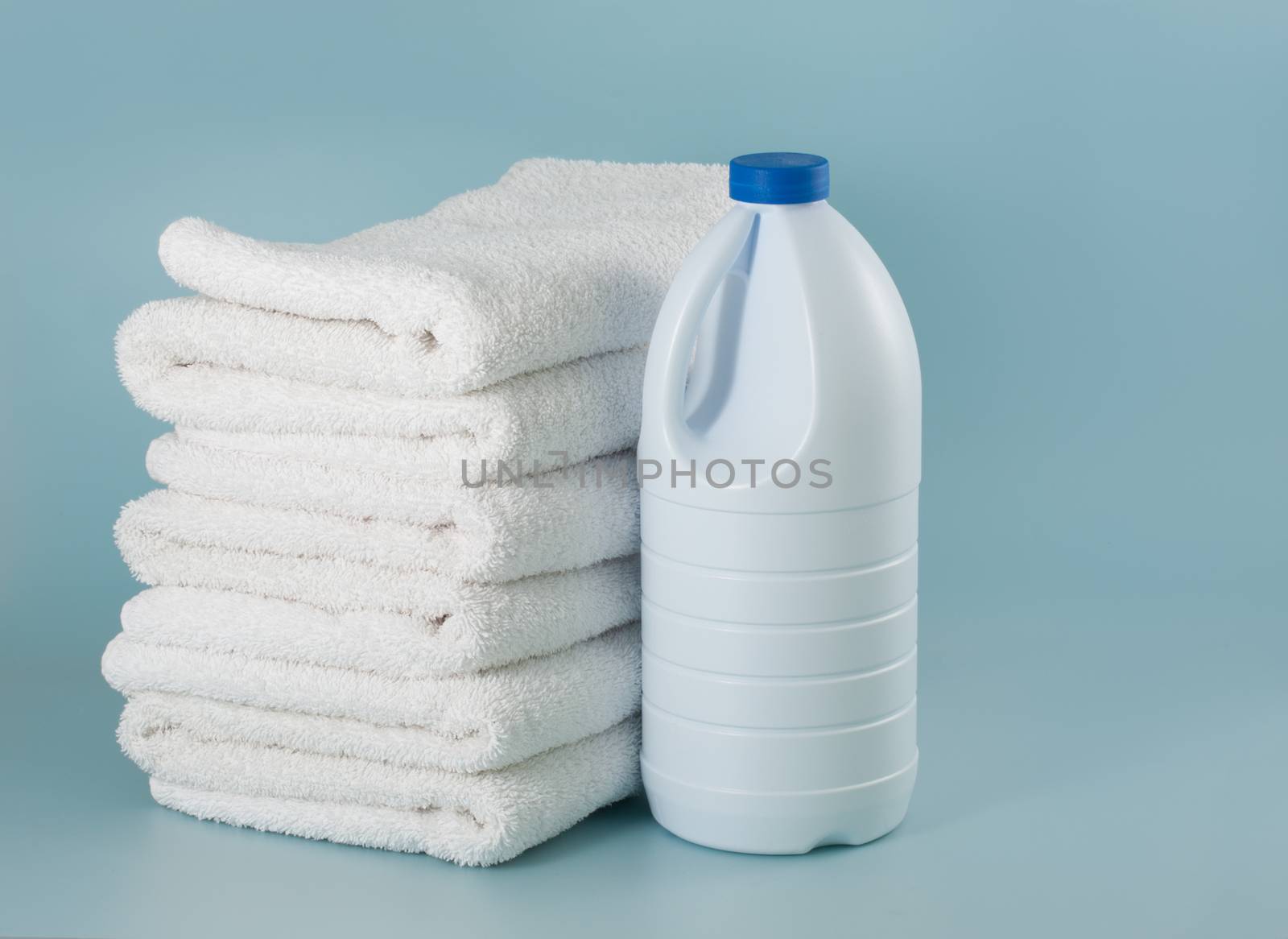 Laundry white bleach bottle place beside stack of bath towel