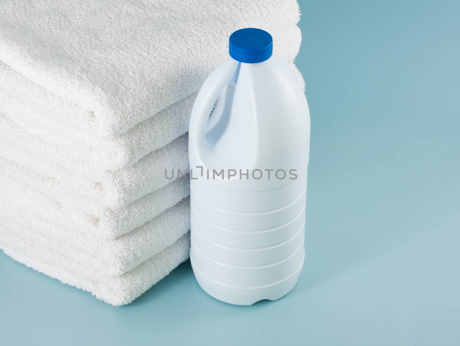 Laundry white bleach bottle place beside stack of bath towel