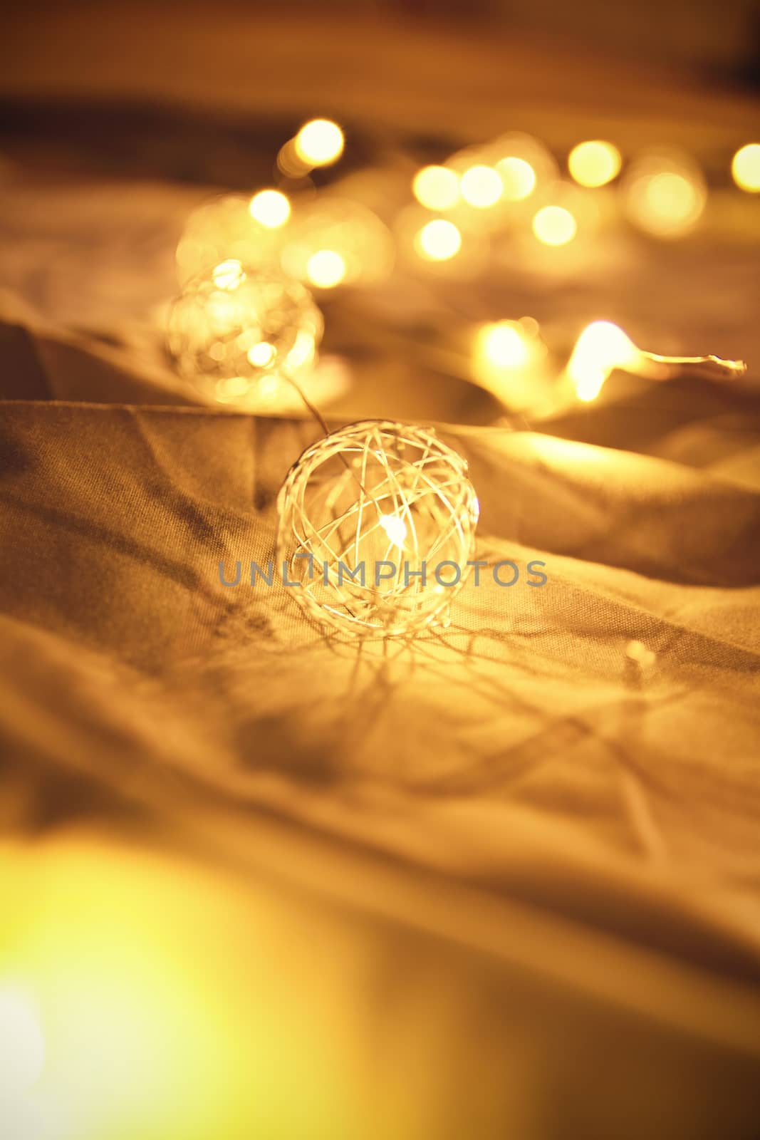 Blurred golden Christmas lights on rumpled bed sheets by Mendelex