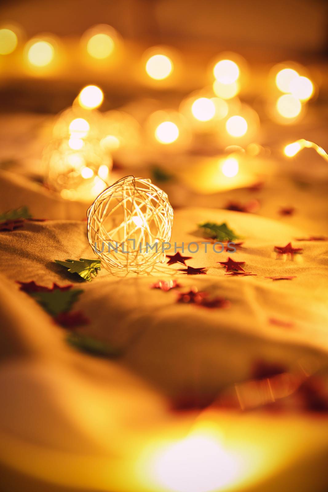 Blurred golden Christmas lights with decorations on rumpled bed sheets by Mendelex