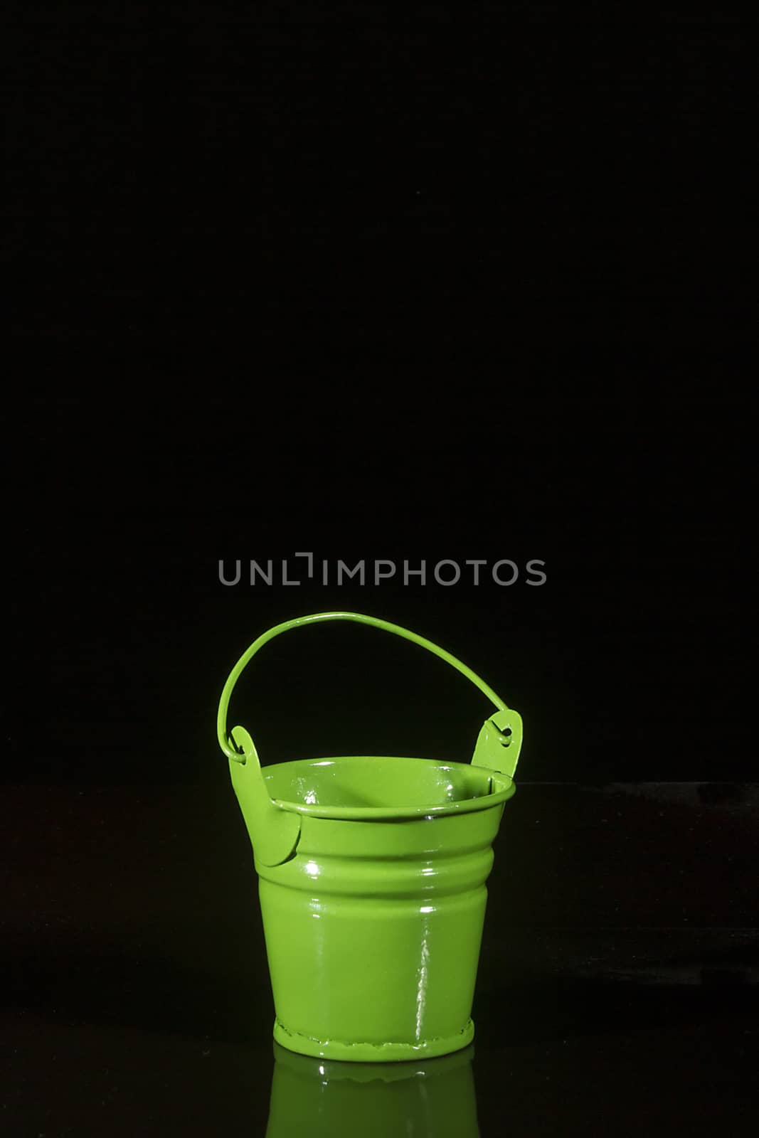 Small green bucket on a black reflective background